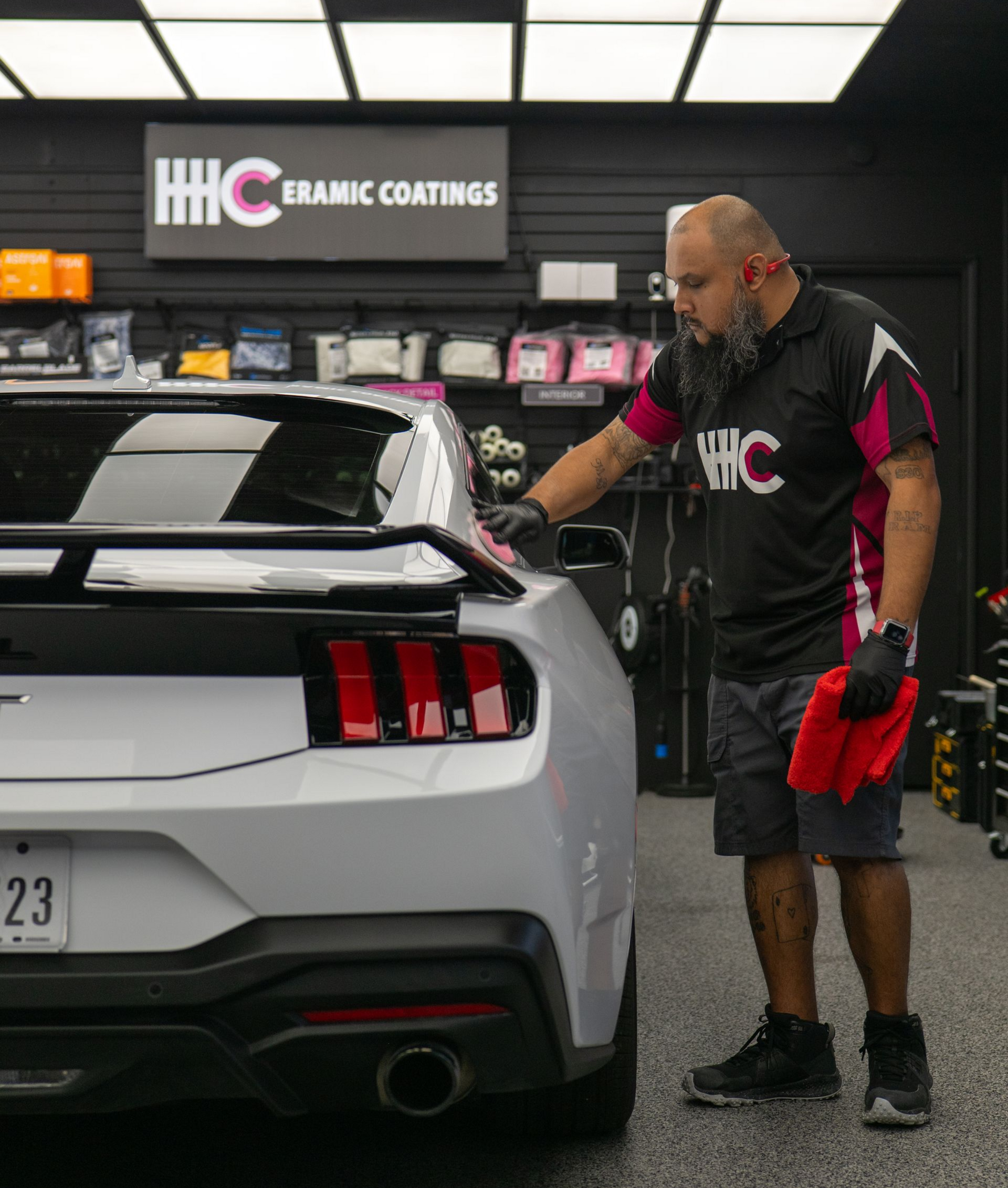 Detailer polishing a white sports car in a ceramic coatings shop