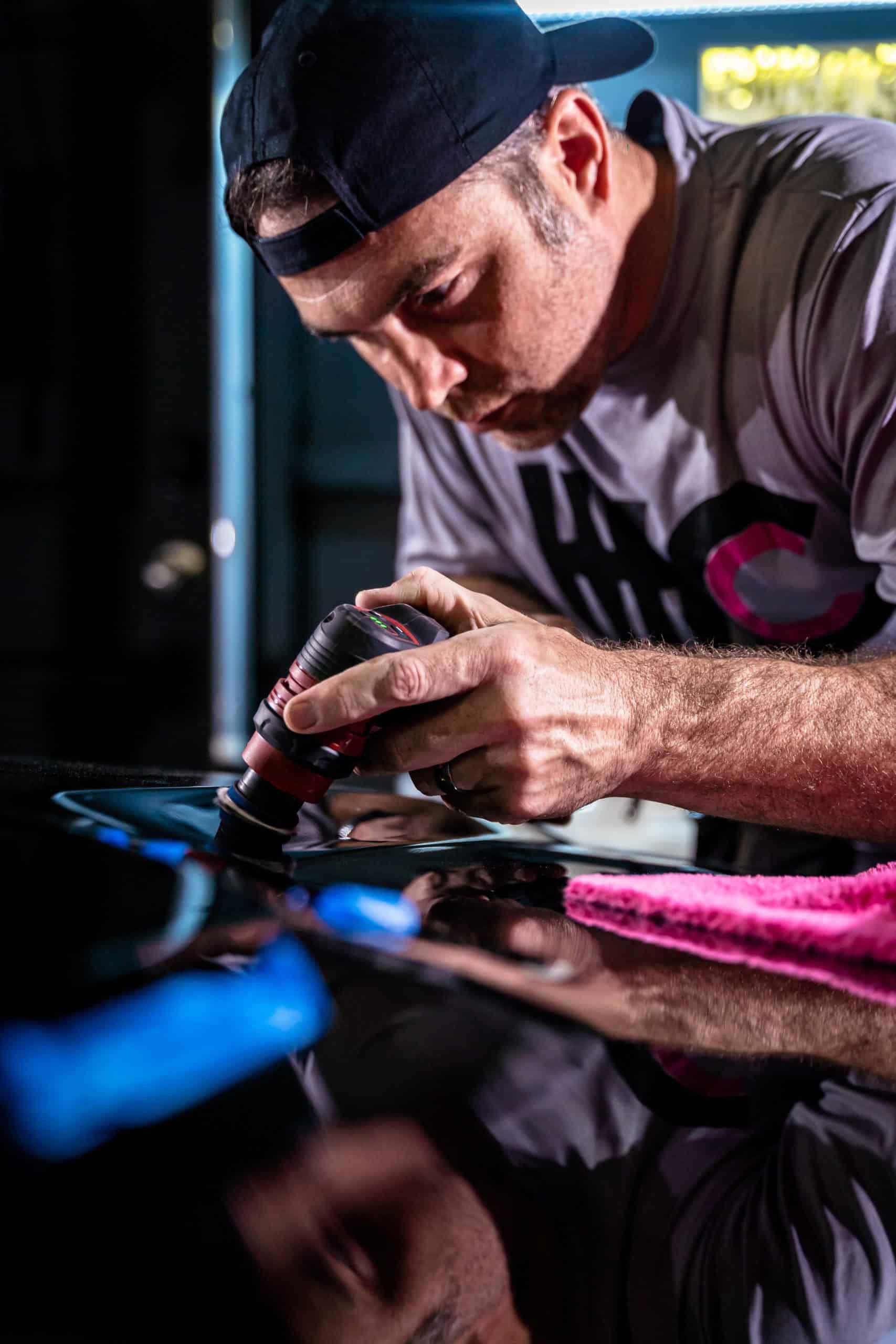 A man is polishing a car with a machine.