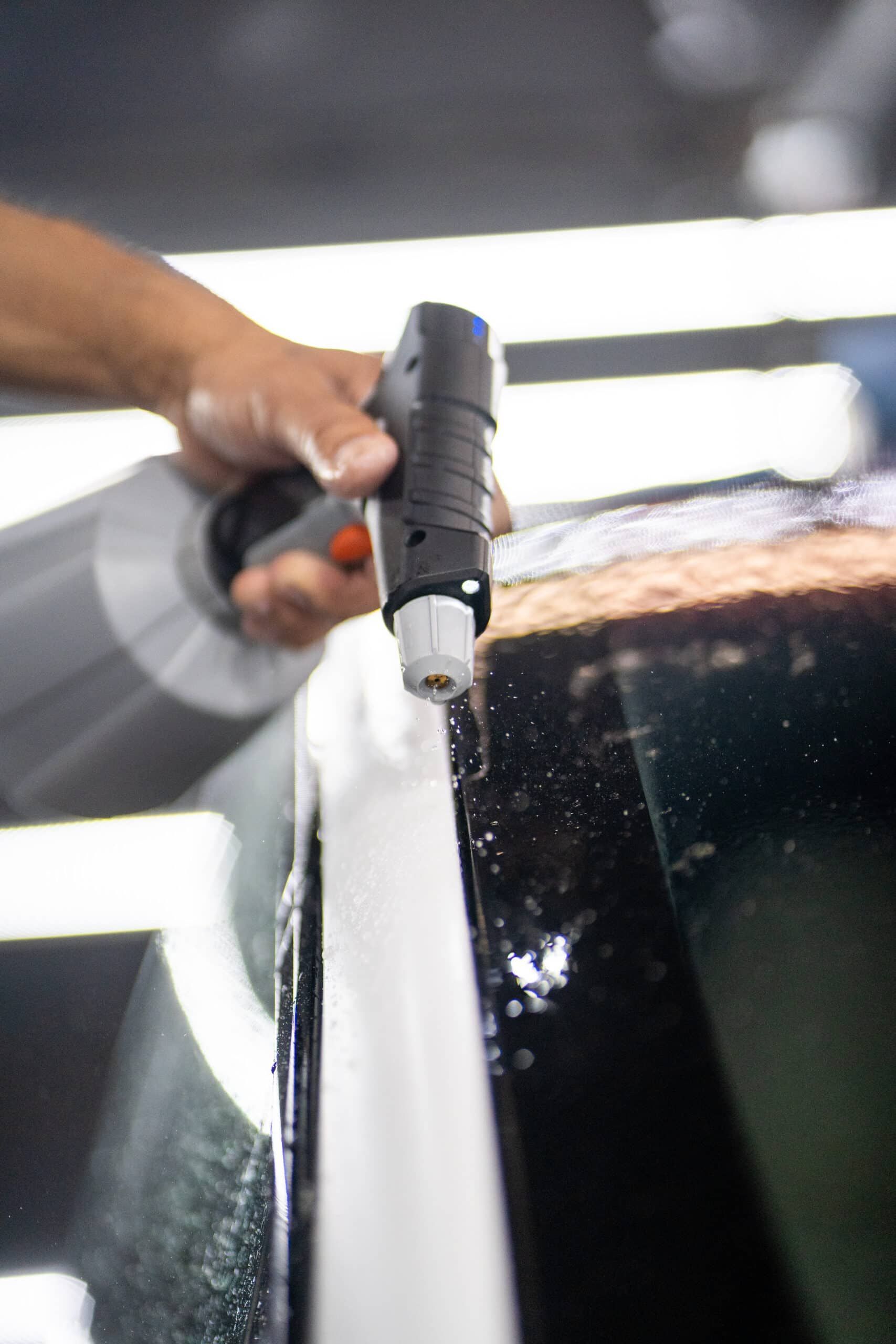 A person is spraying a car with a spray bottle.