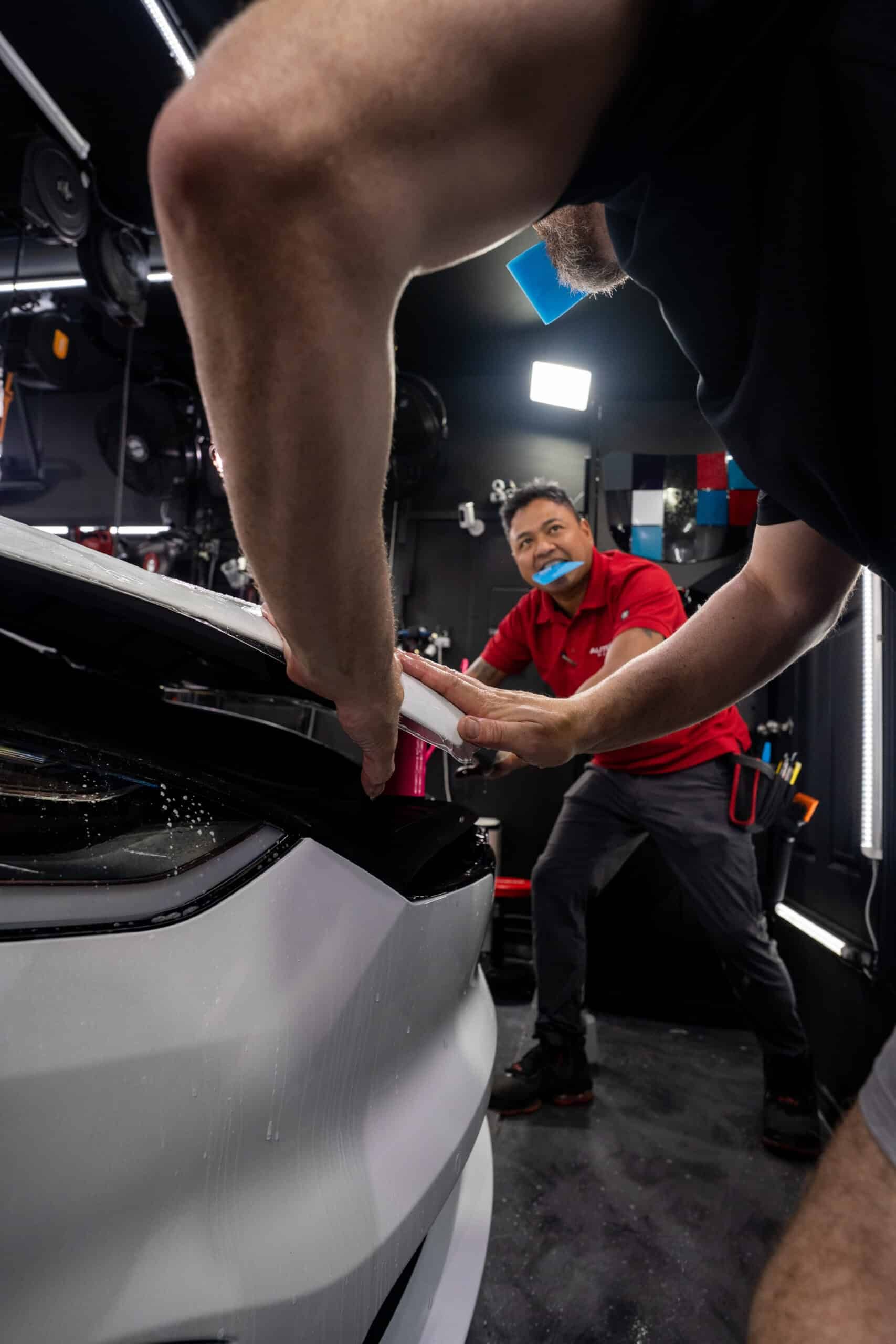 Two men are working on a tesla model 3 in a garage.
