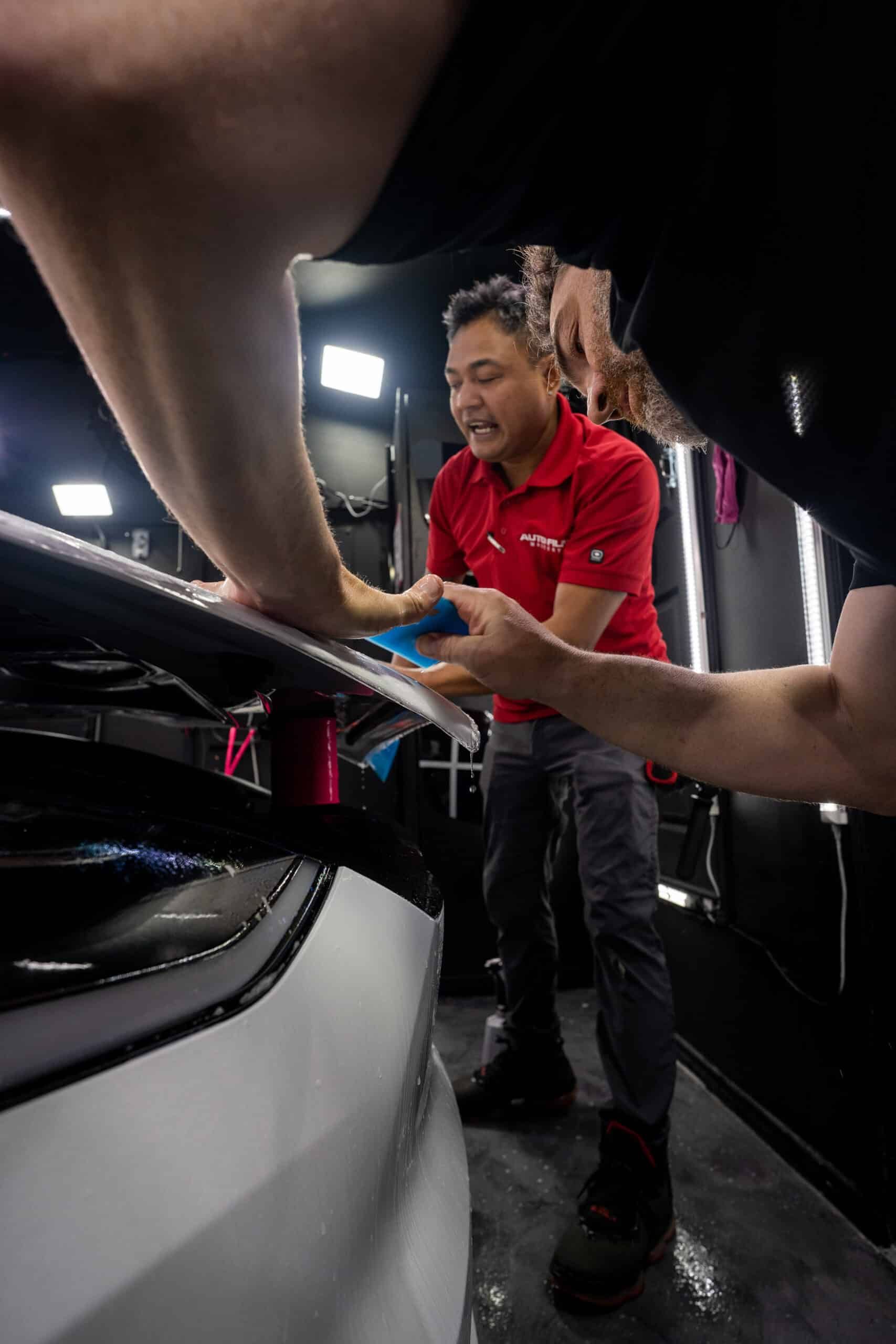 A man in a red shirt is working on a car.