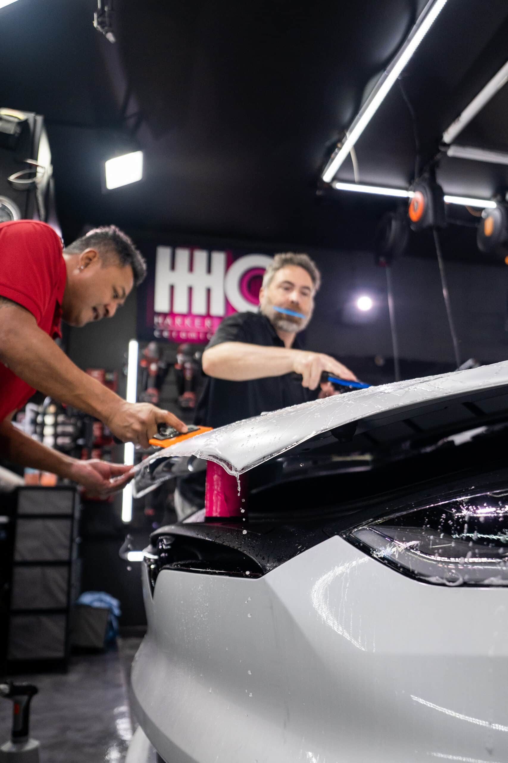 Two men are working on a car in a garage.