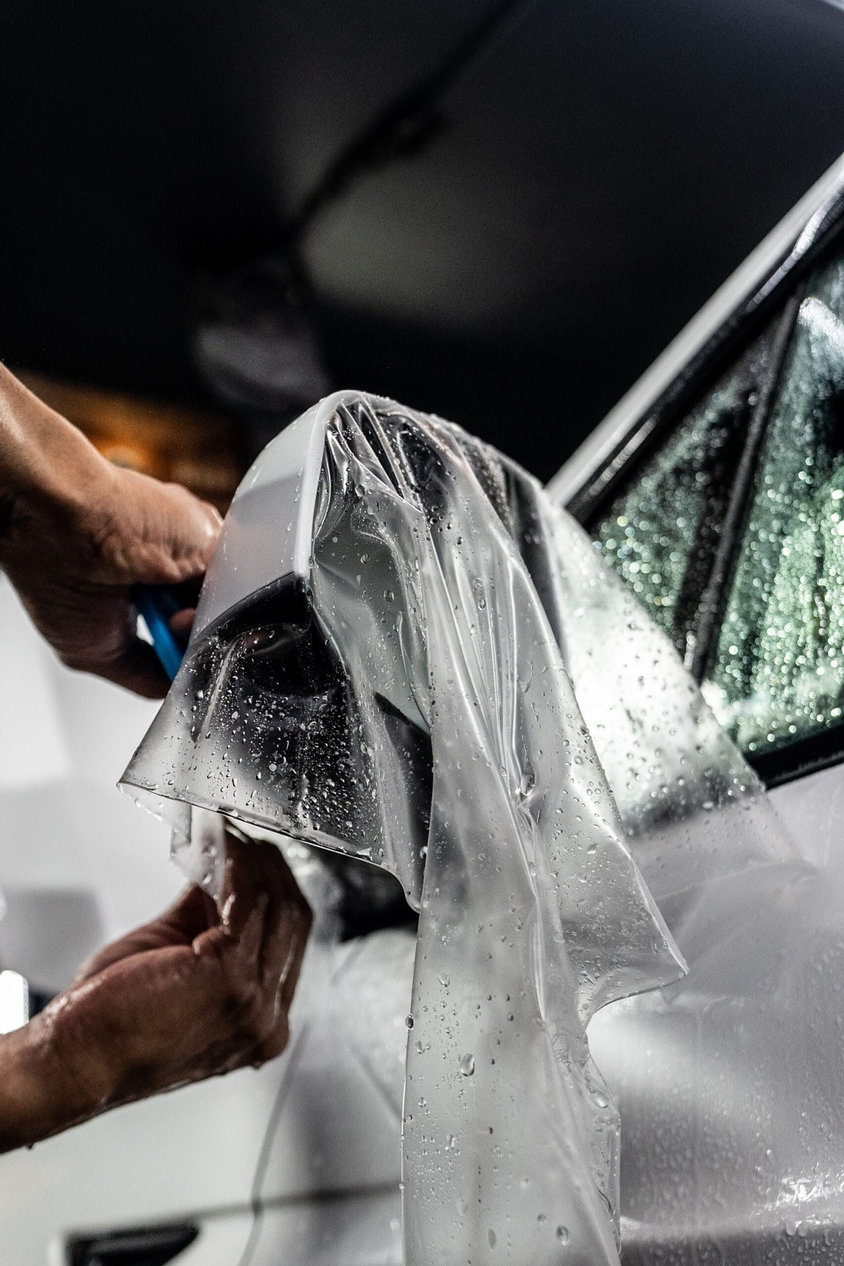 A person is wrapping a car with plastic wrap.