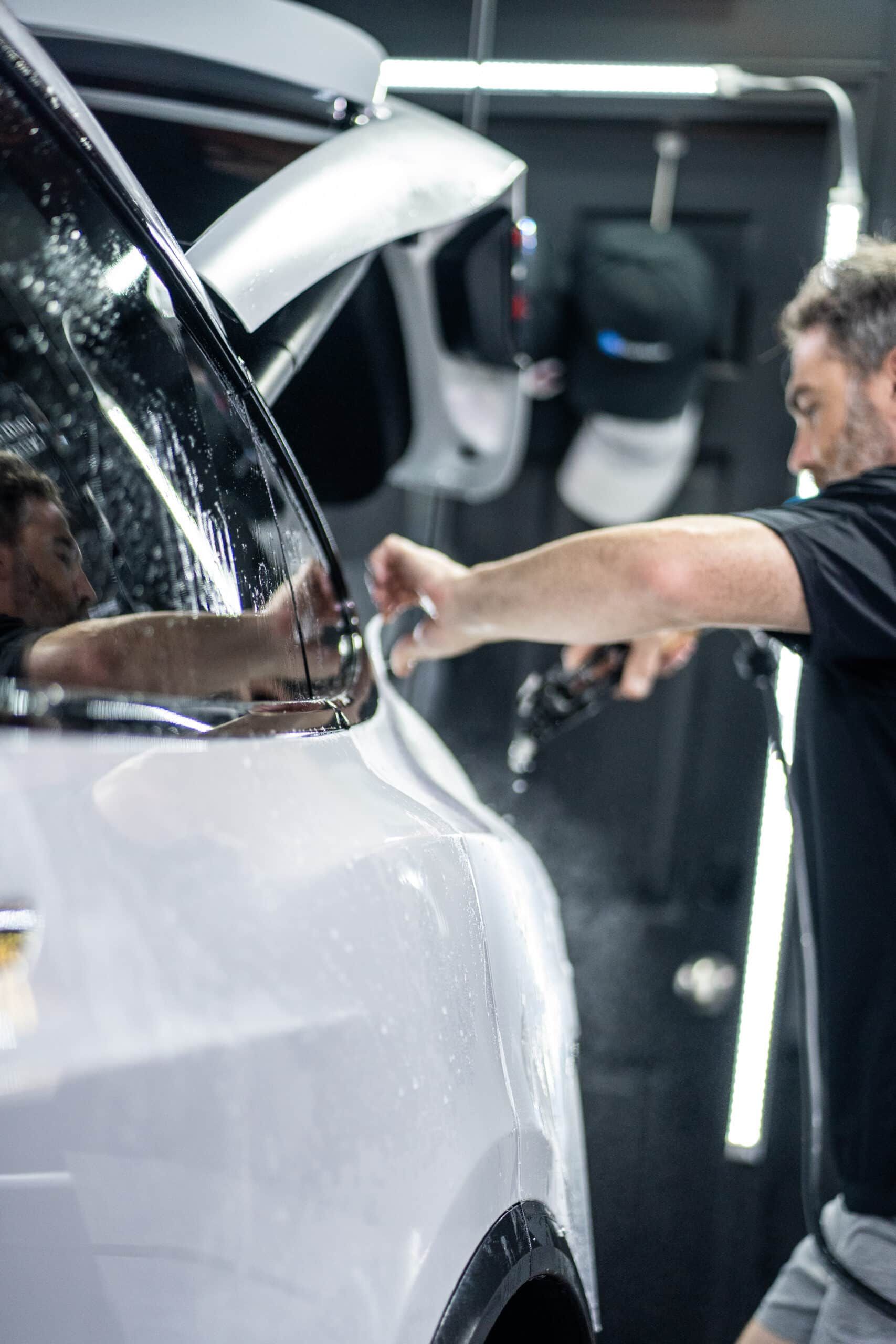 A man is working on a white car in a garage.