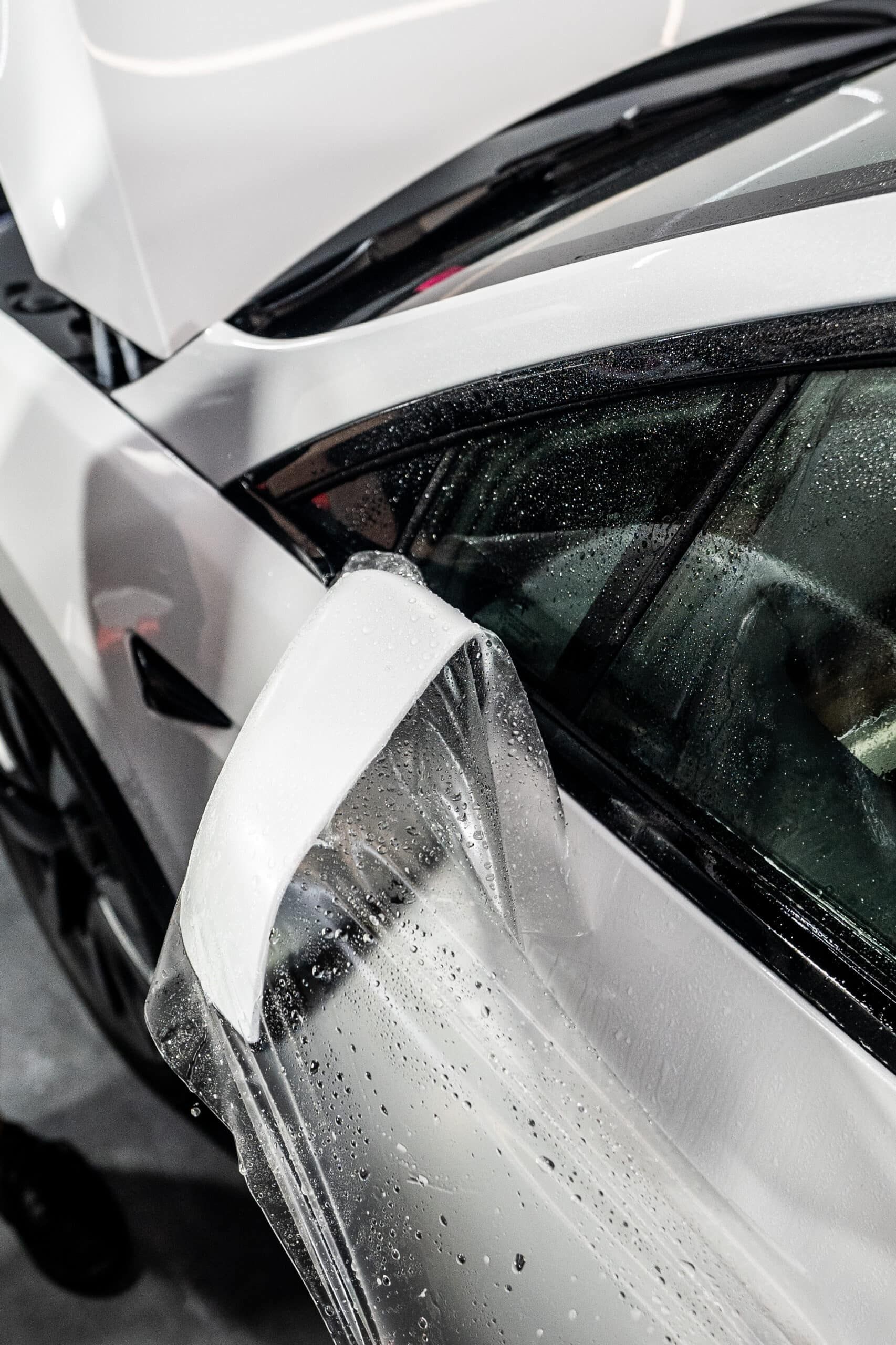 A close up of a white car covered in plastic.