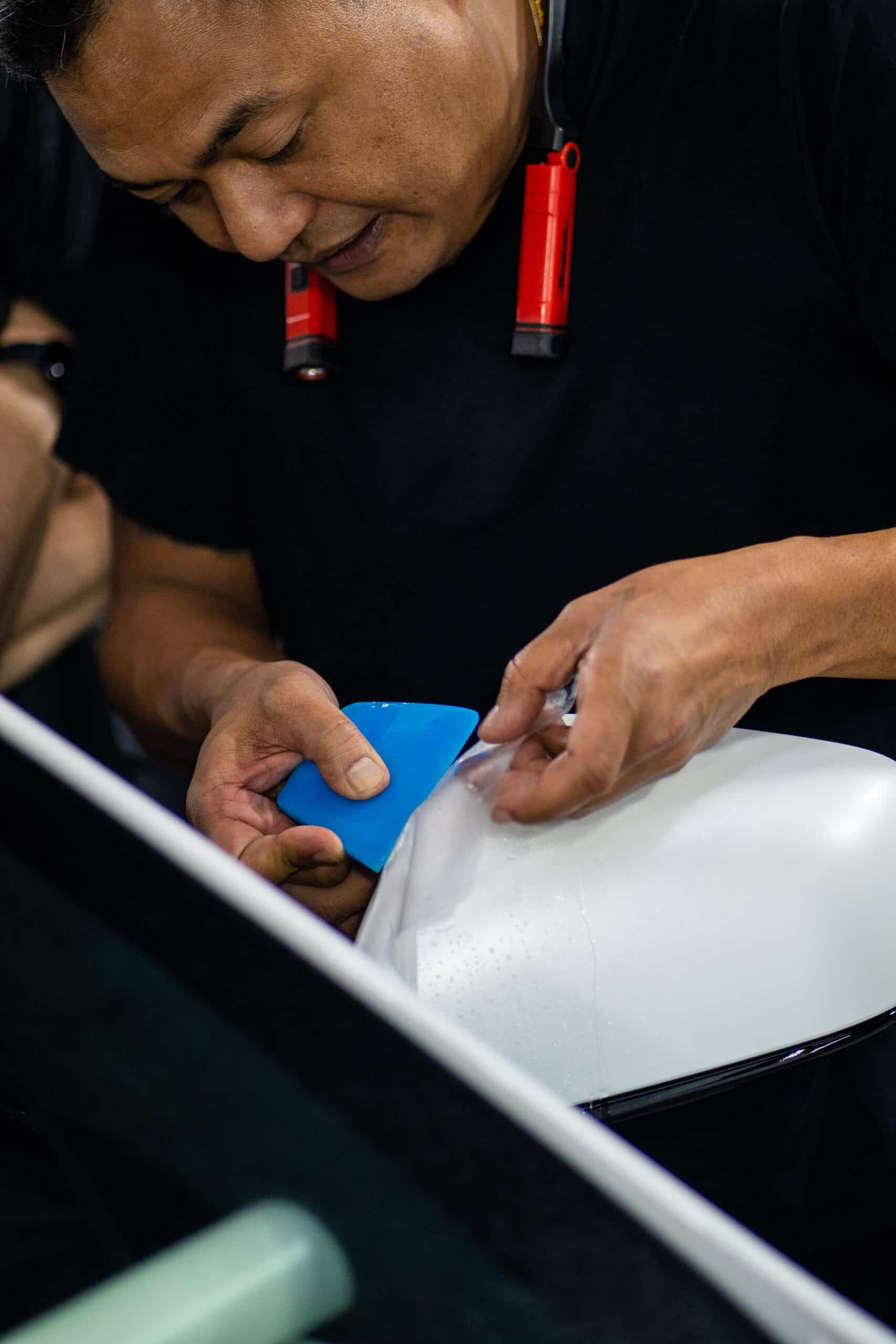 A man is wrapping a car with a blue sponge.