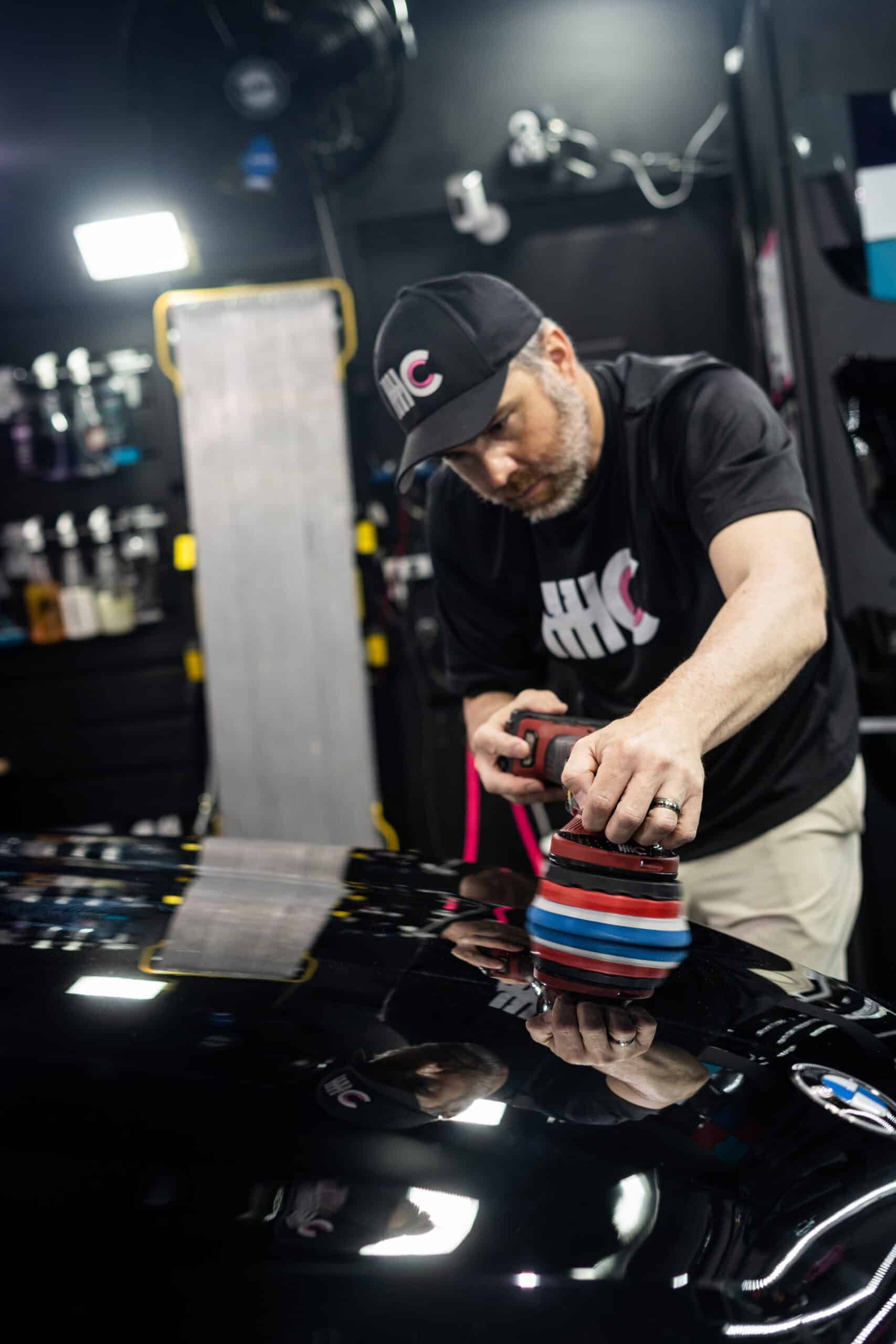 A man is polishing a black car with a machine.