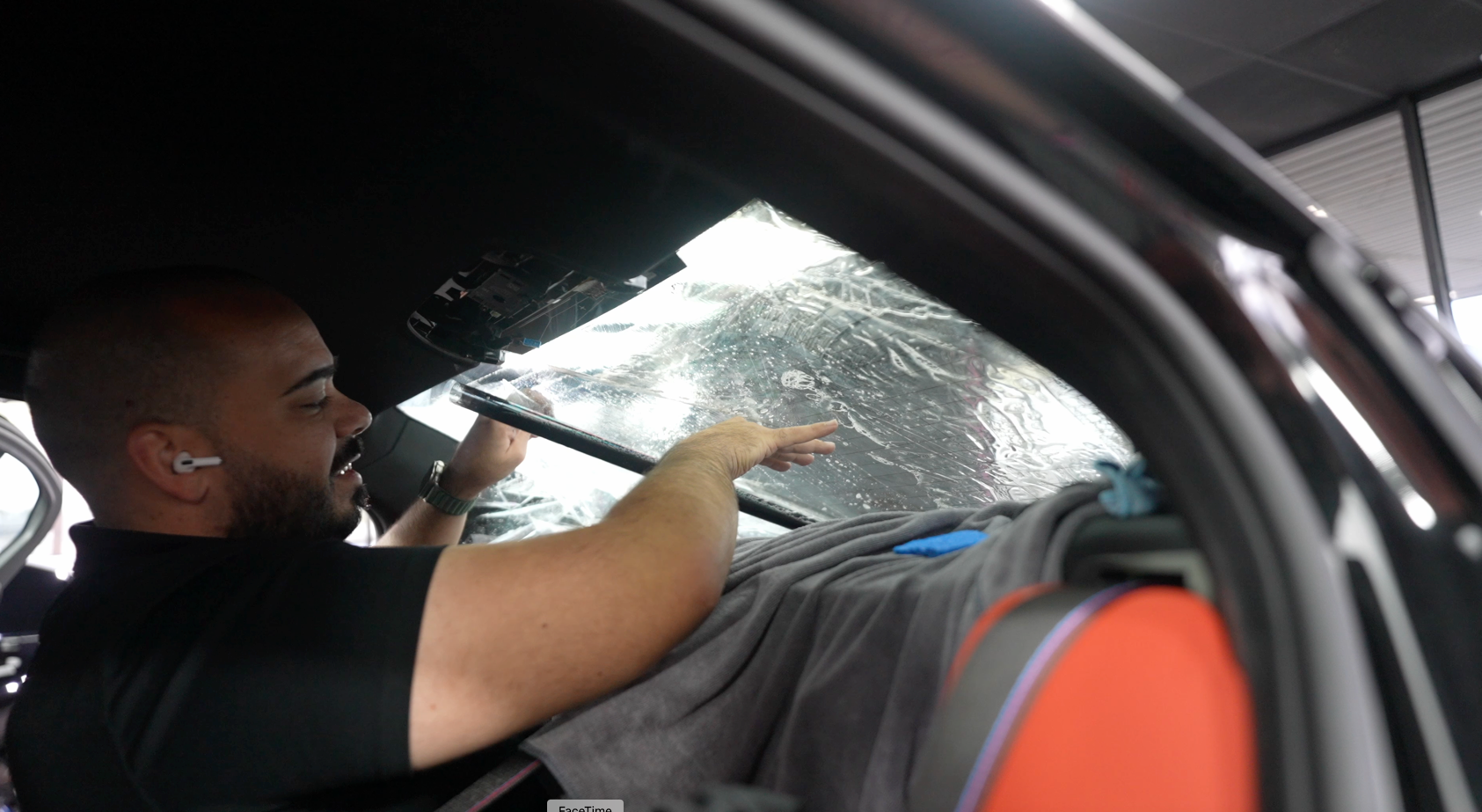 A man is applying window tinting to a car window.