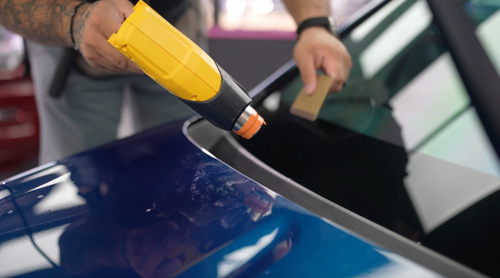 Window tinting installation for a blue vehicle.