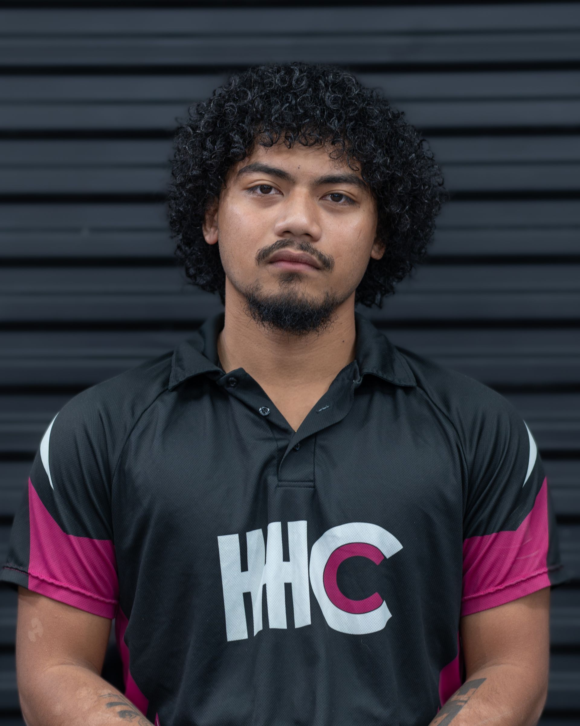 Man with curly hair in a maroon and black shirt with