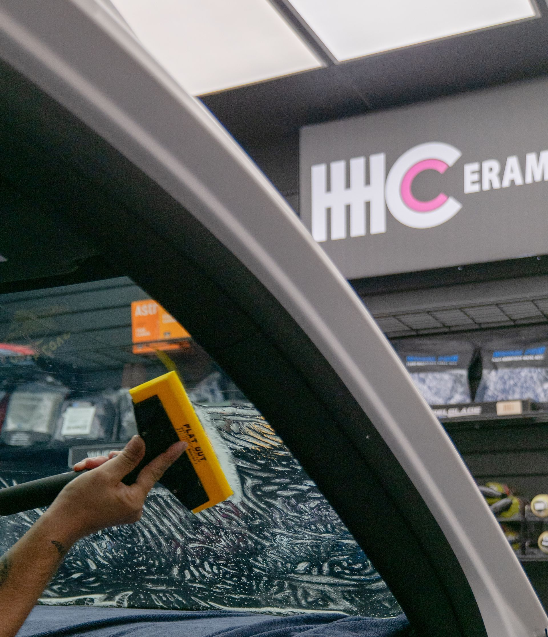 A man is cleaning the front of a black car in a garage.