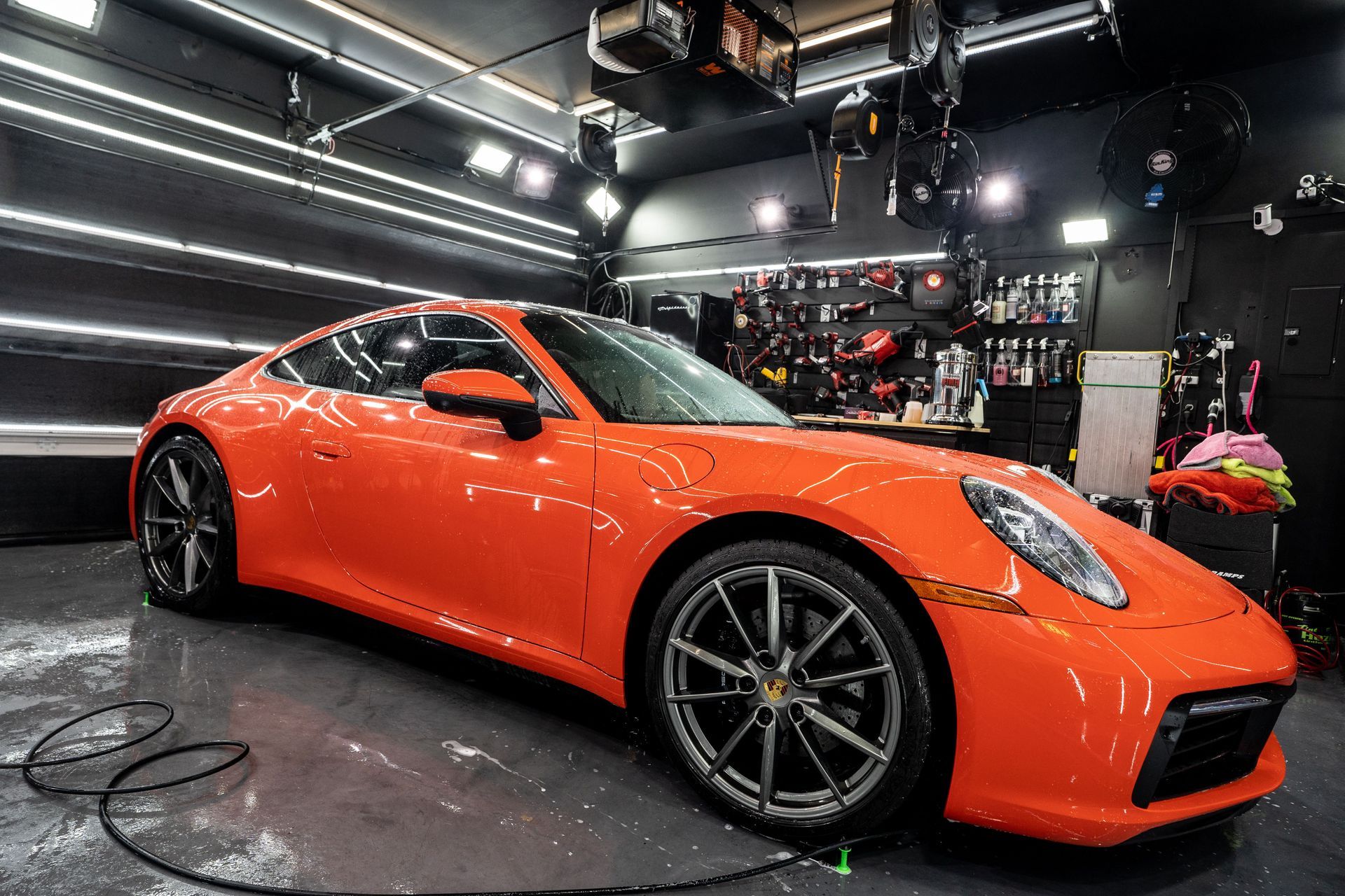 An orange porsche 911 is parked in a garage.