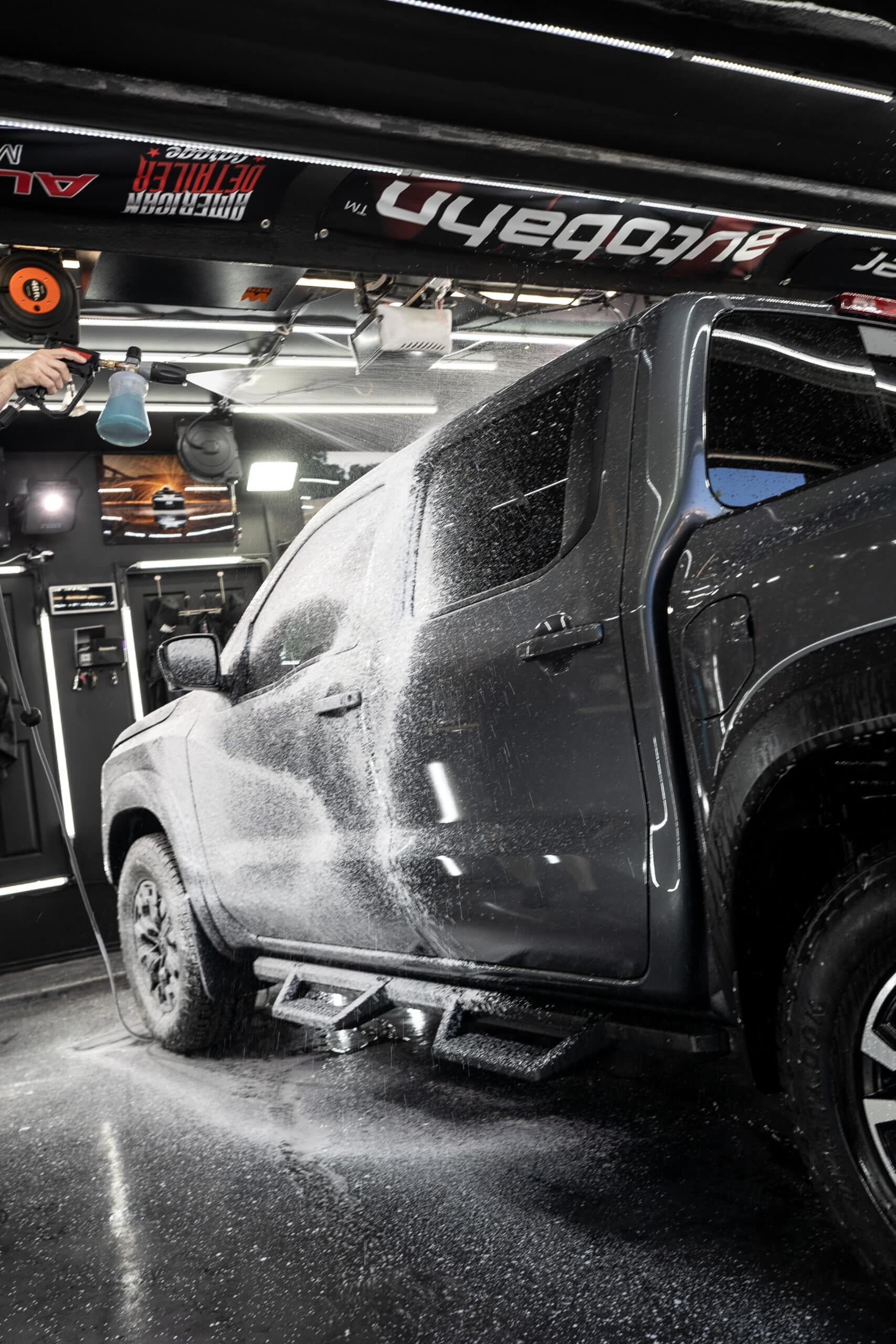 A man is washing a truck in a garage.