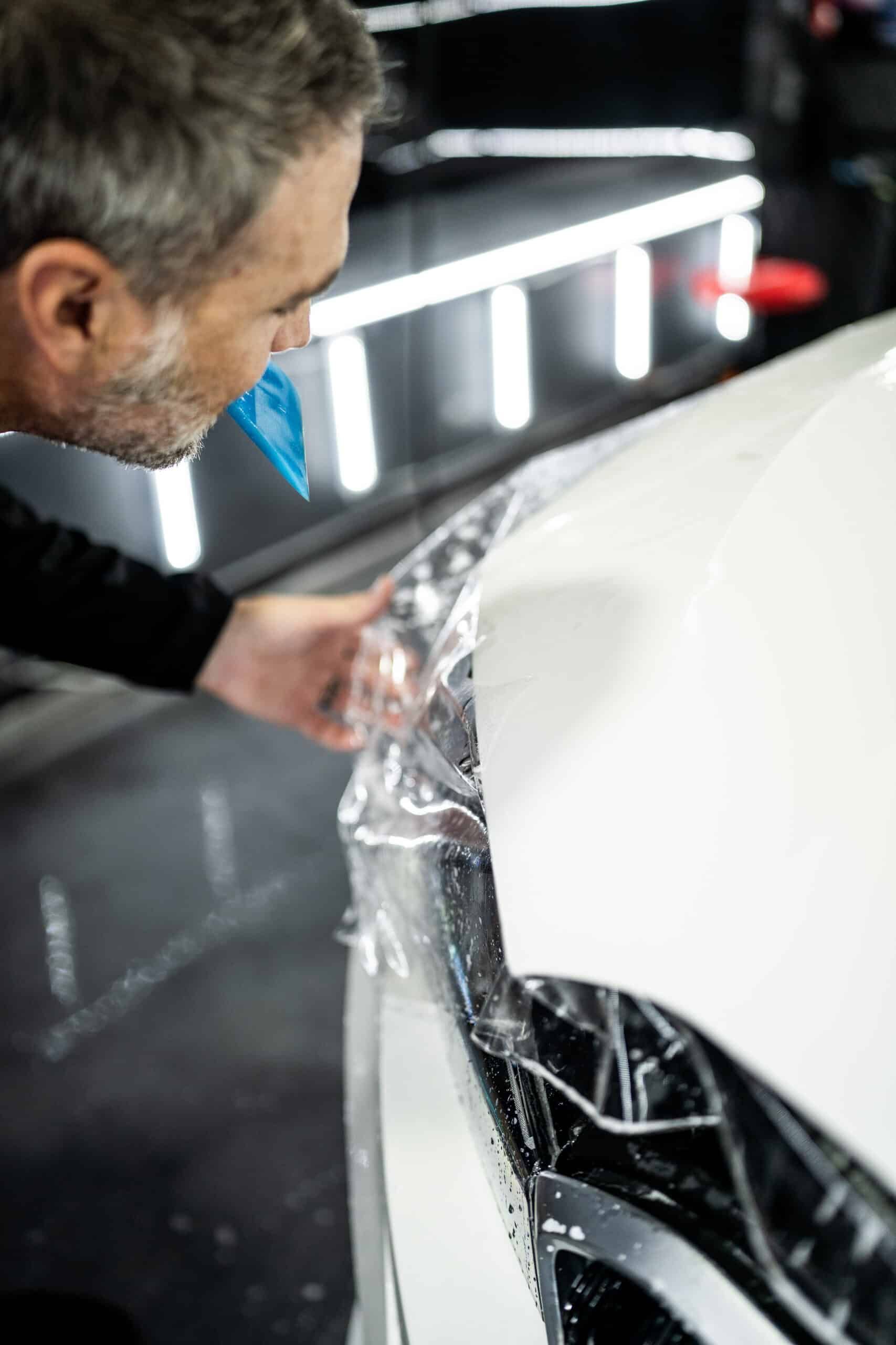 A man is wrapping a car with plastic wrap.
