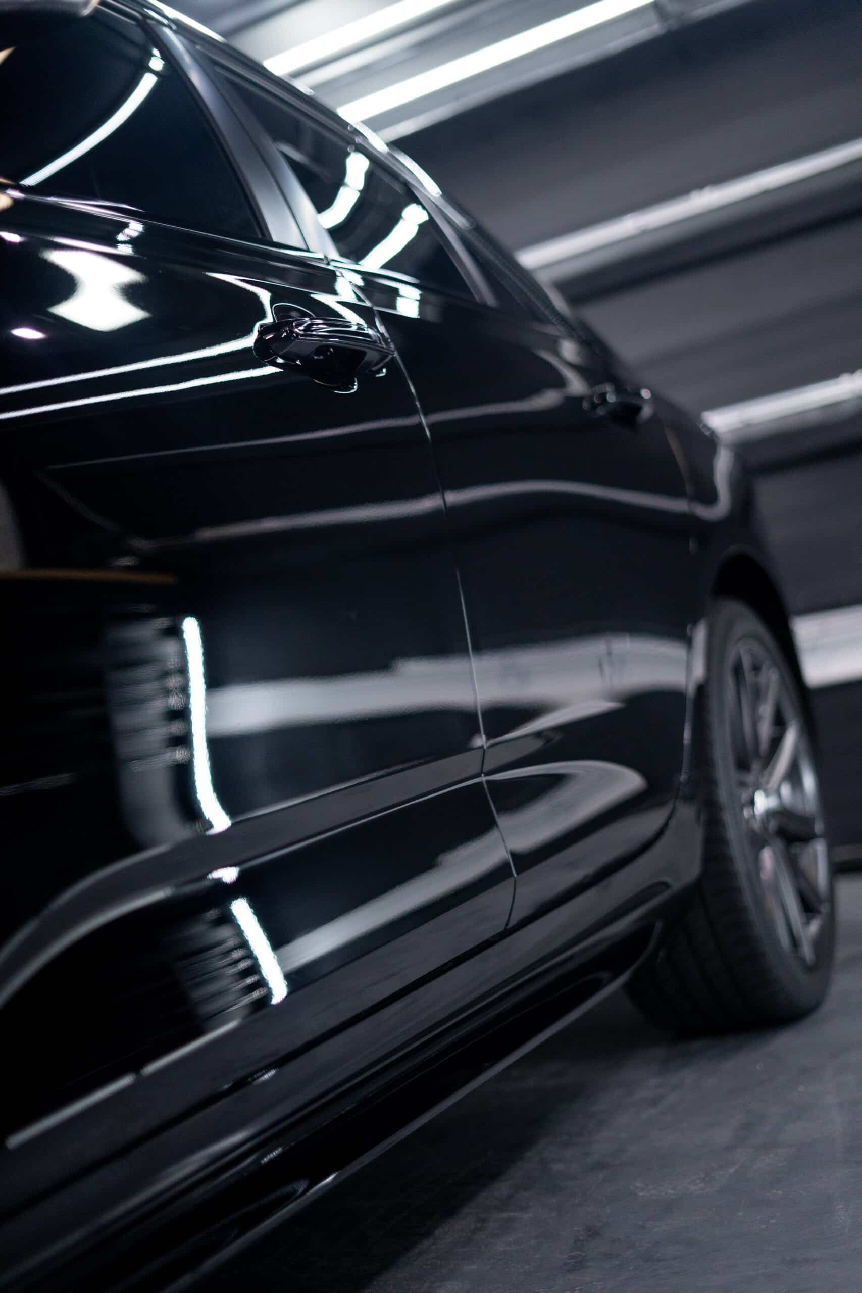 A black car is parked in a garage with the door open