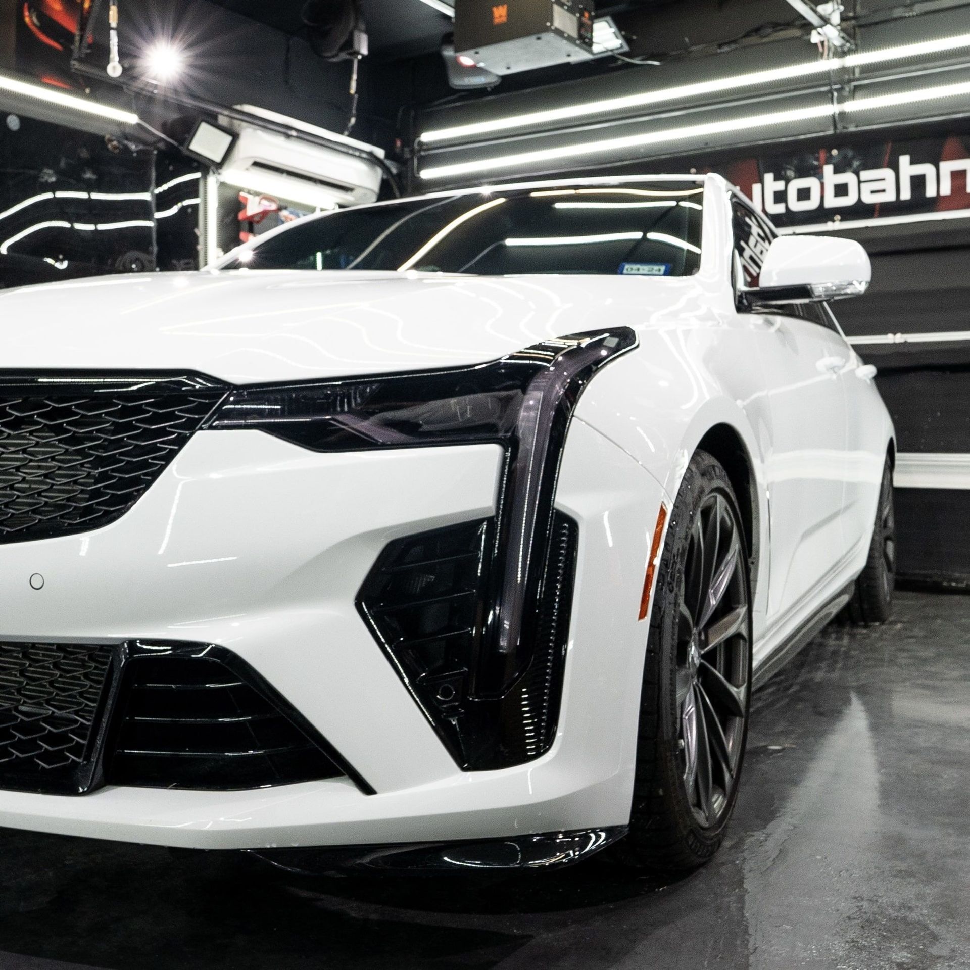 A white car is parked in front of a sign that says tobahn