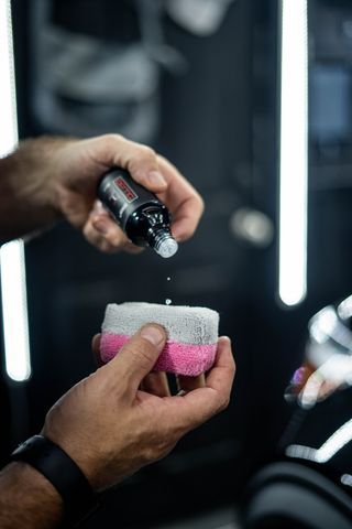 A person is pouring a bottle of liquid on a sponge.