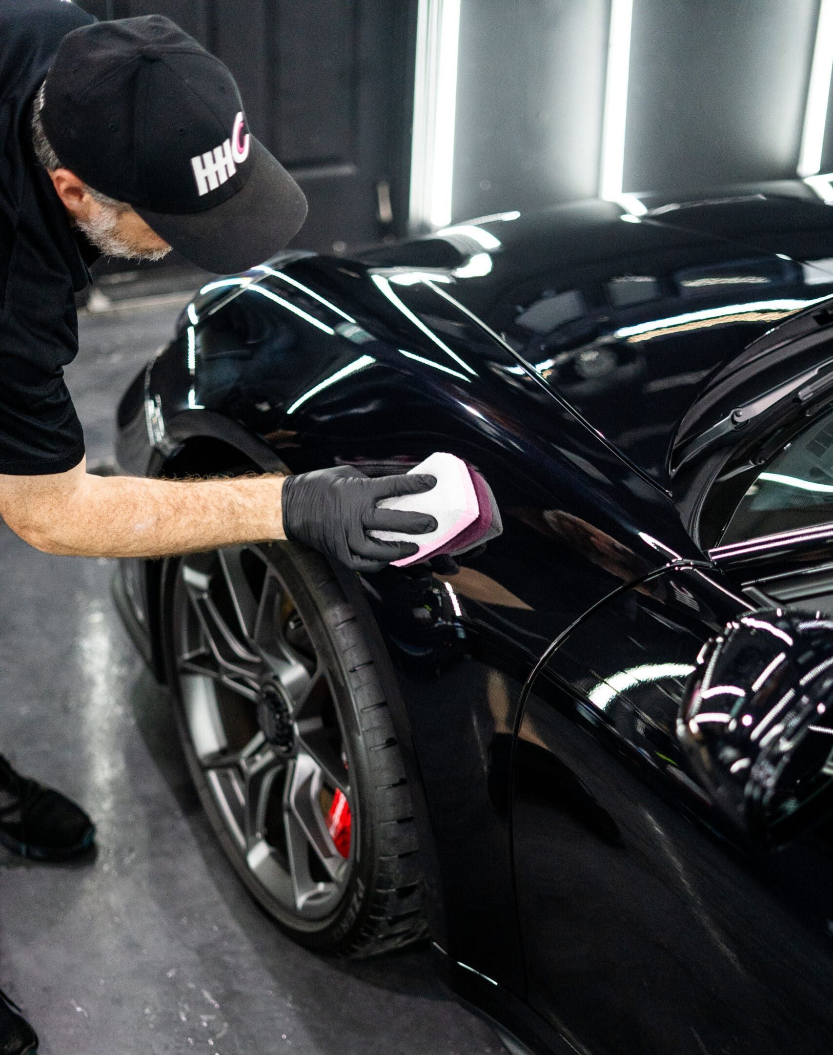 A man is polishing a white car with a machine.