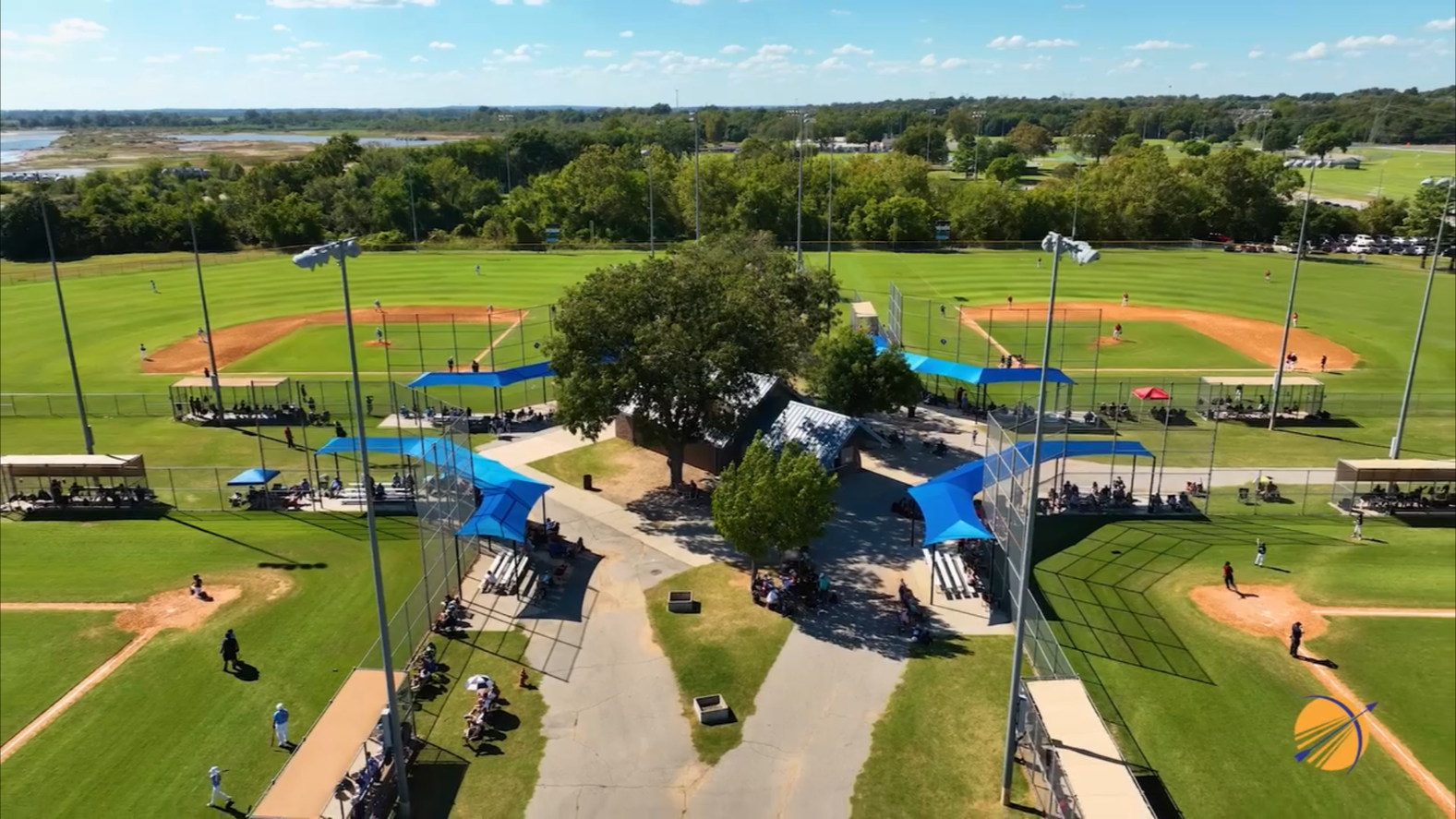 Aerial view of a park with baseball fields, a playground, walking paths, and shaded picnic areas