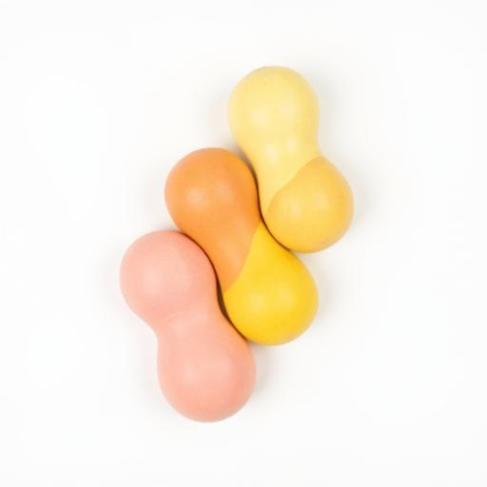 Vier pastellfarbene, ballonförmige Bonbons in Rosa, Orange und Gelb auf weißem Hintergrund