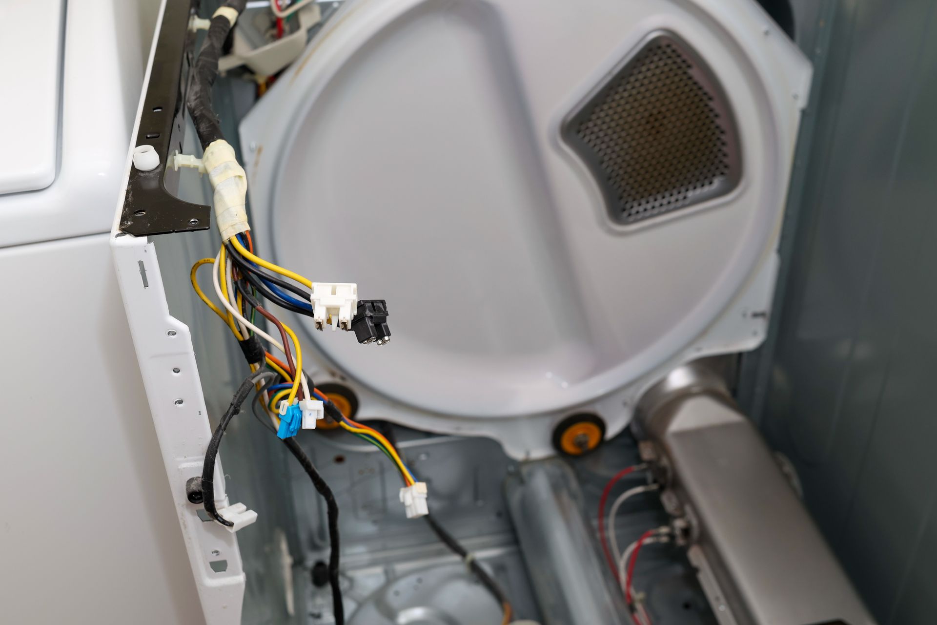 Open washer panel with wiring and components exposed inside a gray appliance
