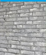 Een close-up van een bakstenen muur met een blauwe lucht op de achtergrond.