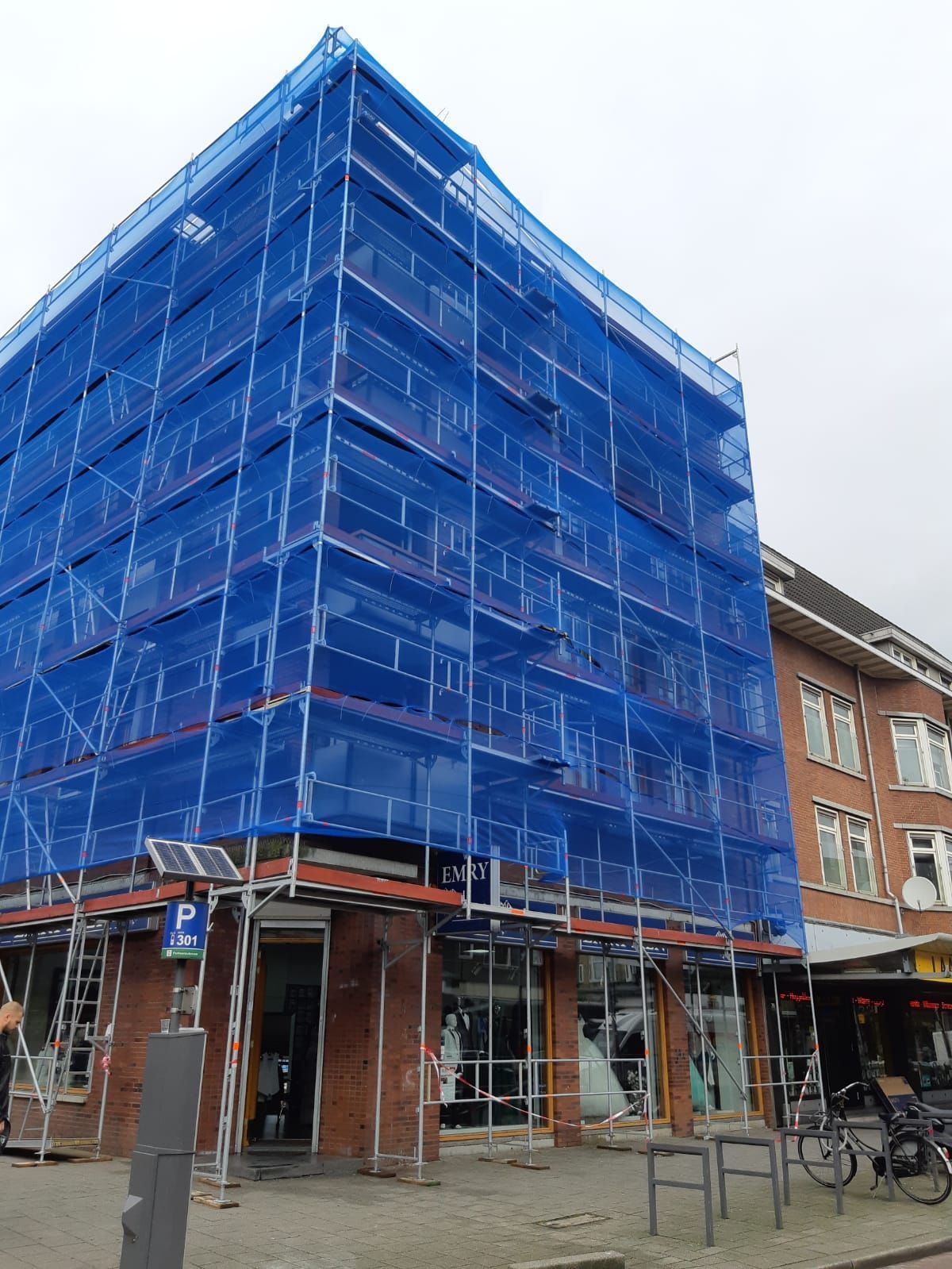 Twee mannen staan op een steiger aan de zijkant van een gebouw