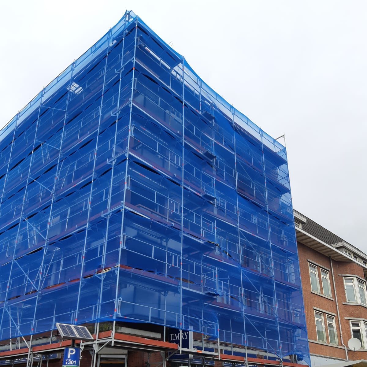 Twee mannen staan op een steiger aan de zijkant van een gebouw