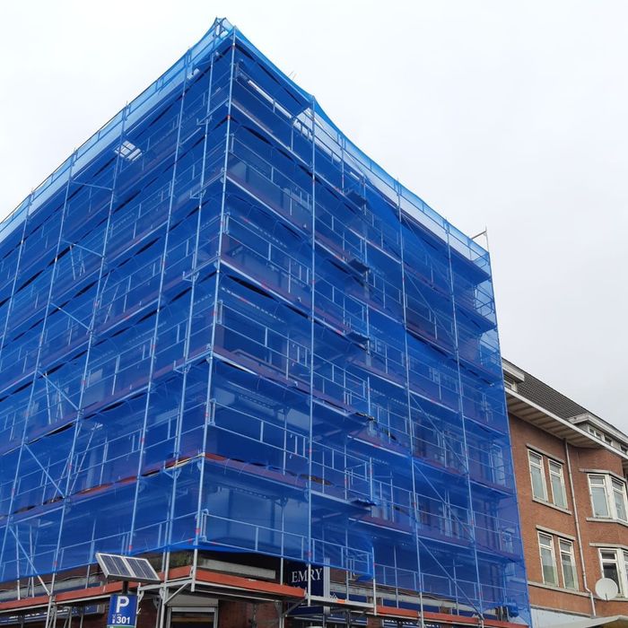 Twee mannen staan op een steiger aan de zijkant van een gebouw
