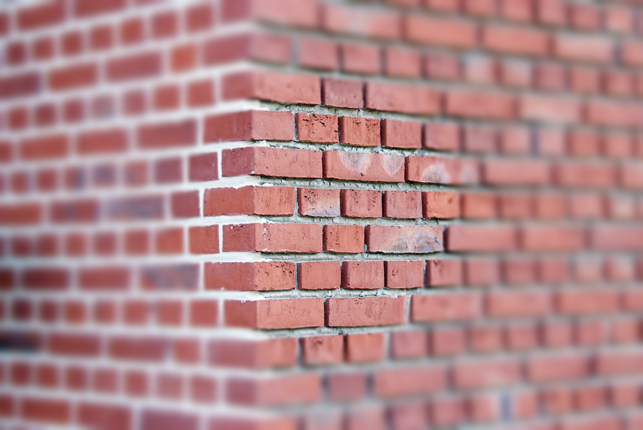 Een close-up van een rode bakstenen muur waarvan een hoek ontbreekt.
