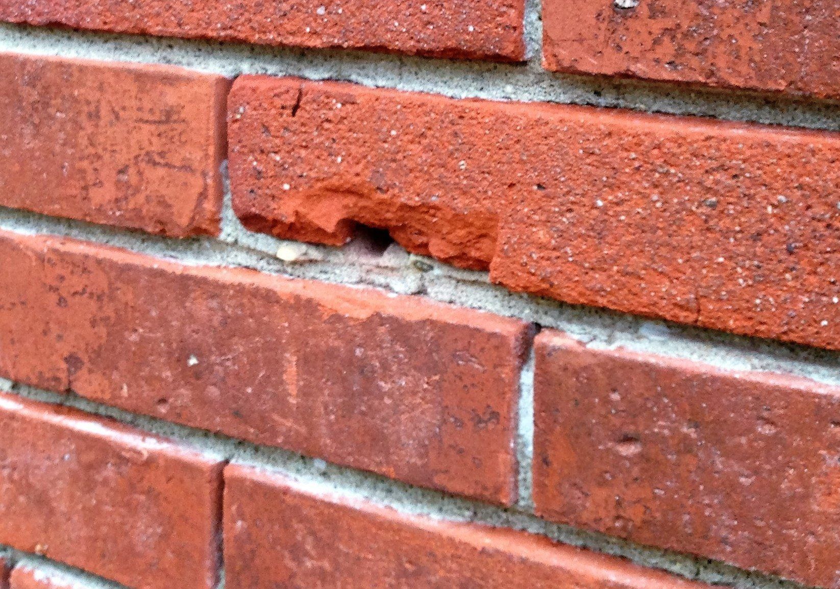 Een close-up van een bakstenen muur met een gat erin.