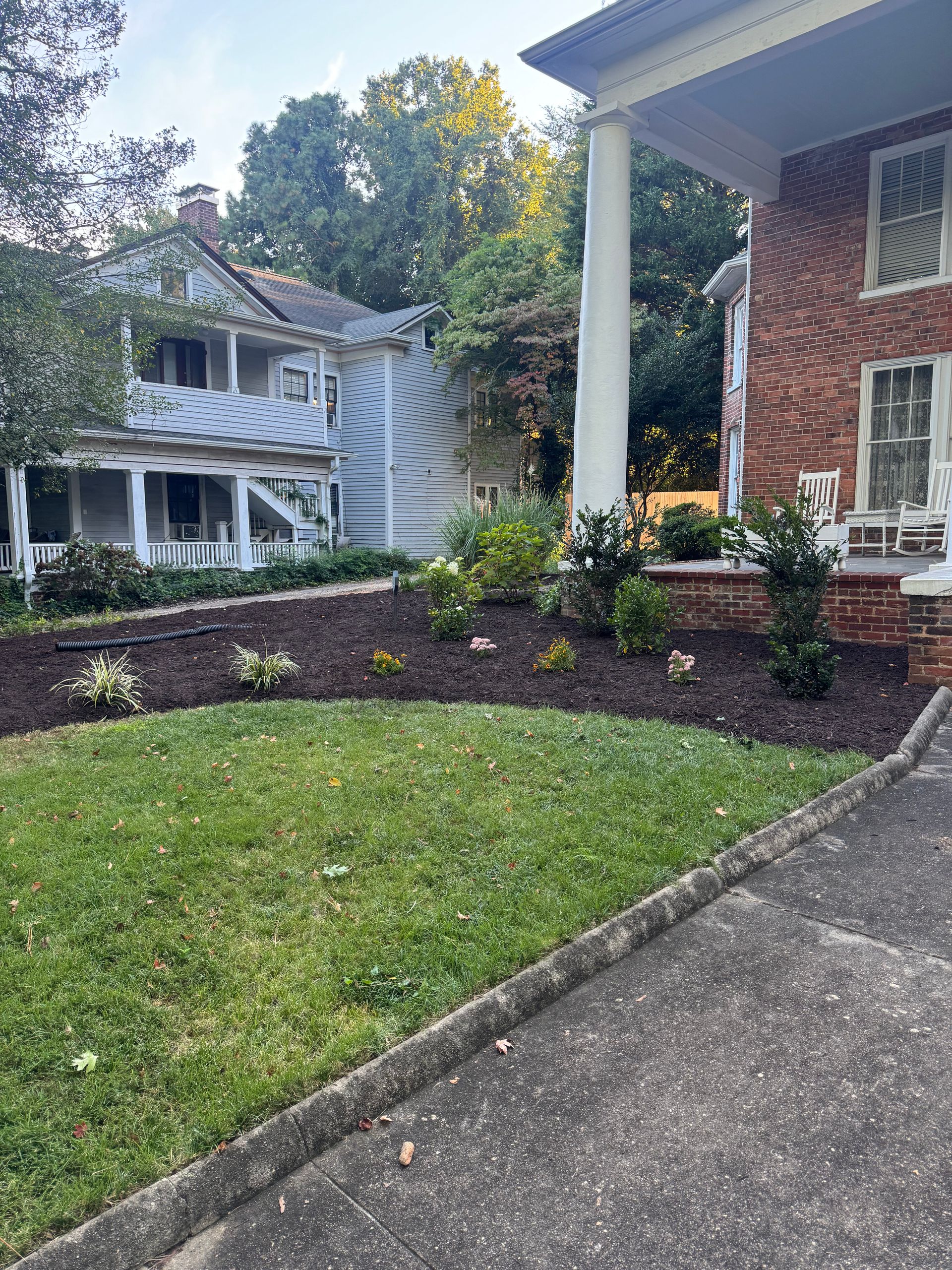 Front yard with house porch, brick exterior, stone walkway, and landscaped mulch beds.