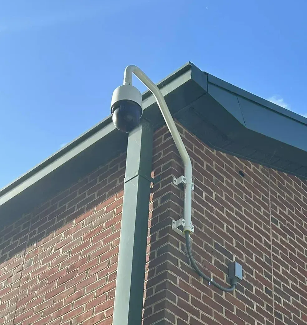 Security camera mounted on a brick building corner under a blue sky.