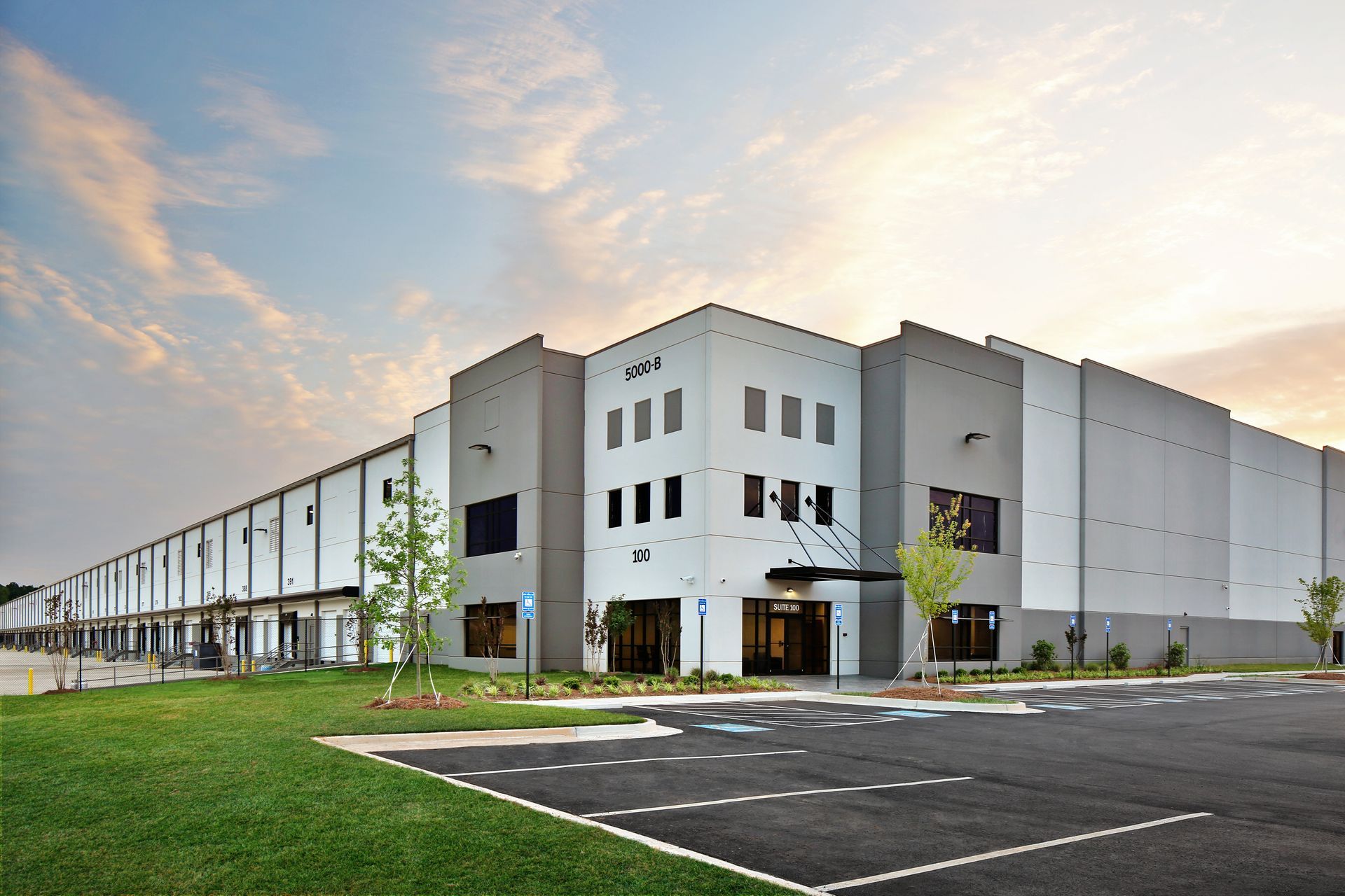 A large warehouse building with a parking lot in front of it