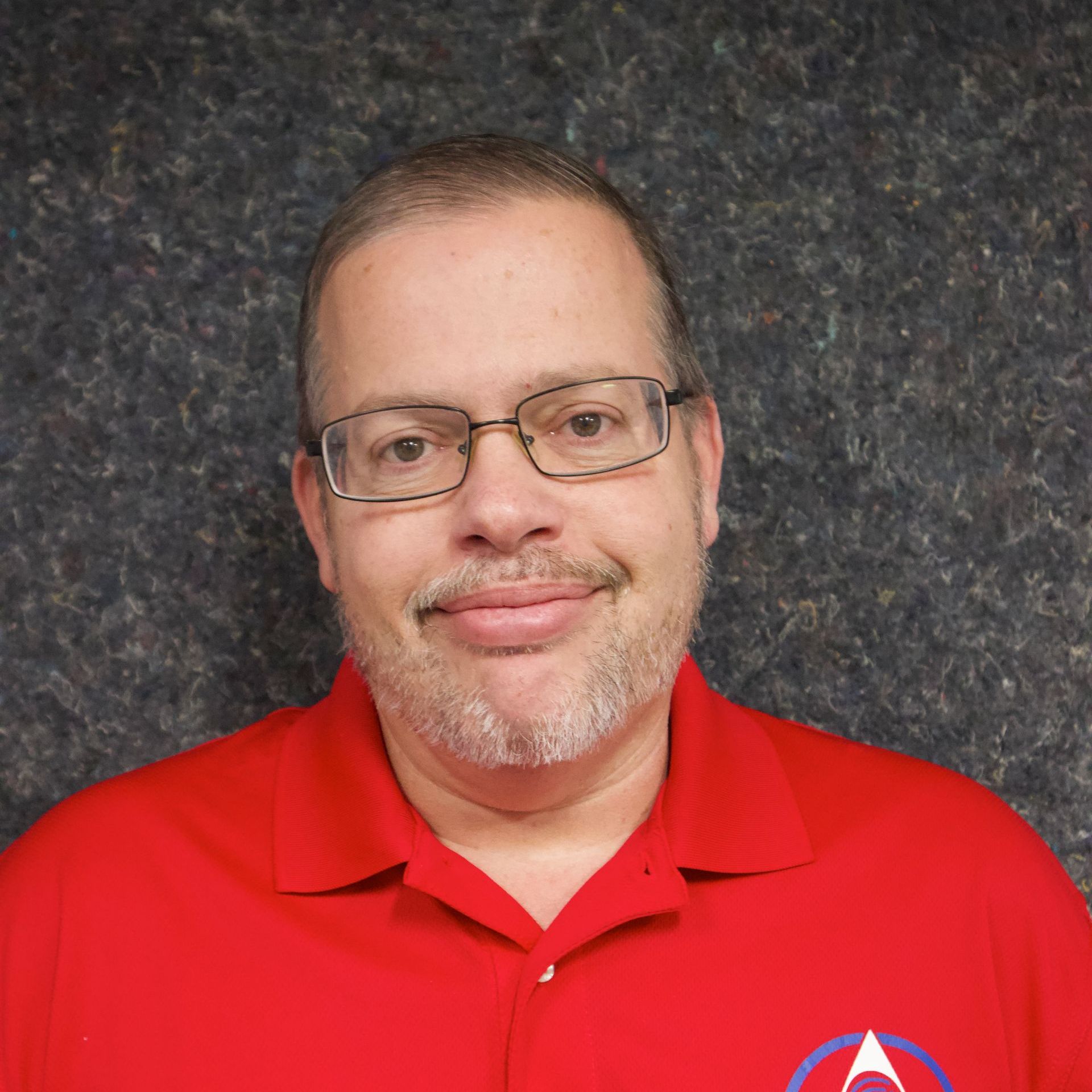 A man with glasses and a beard is wearing a red shirt