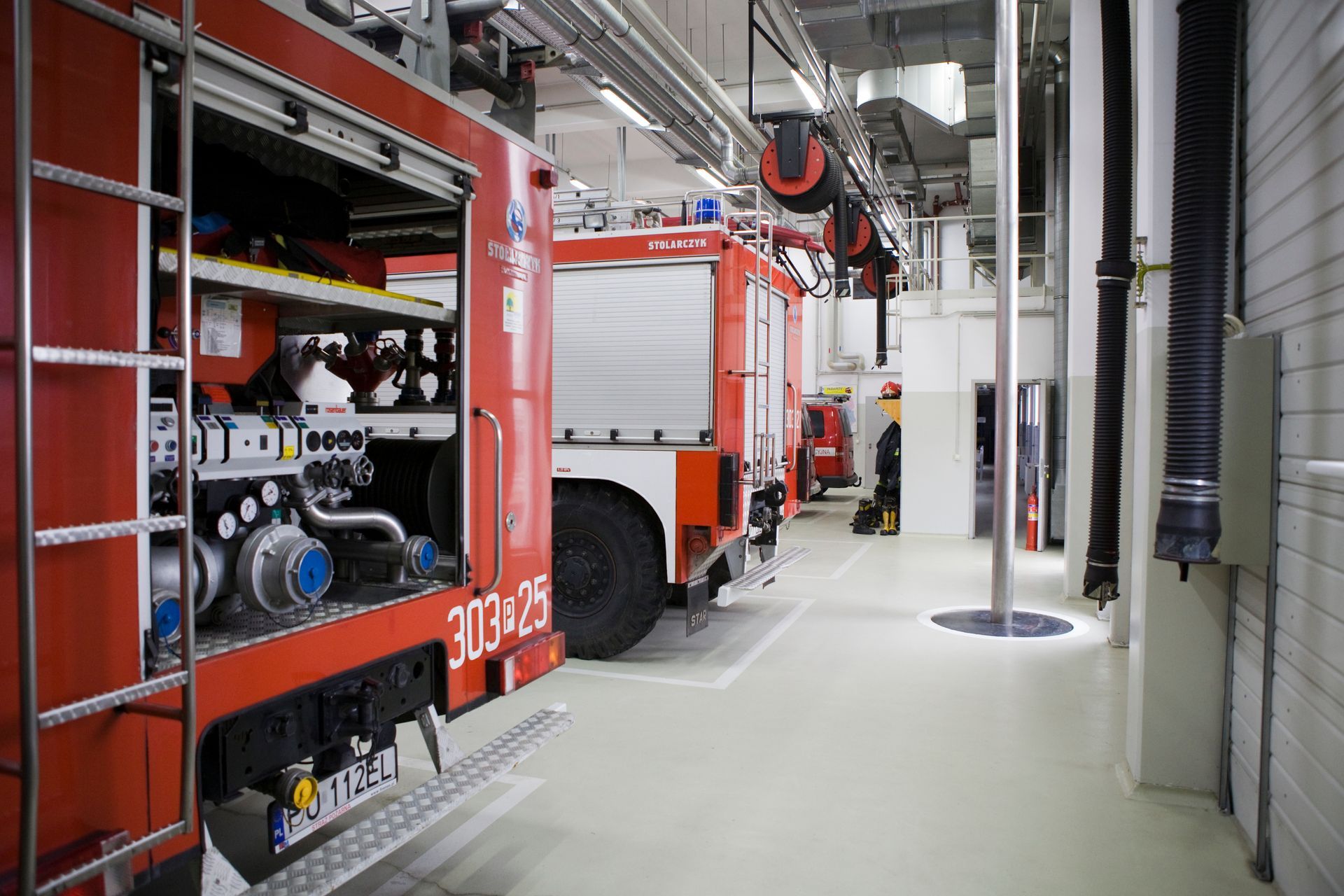 A row of fire trucks are parked in a garage.
