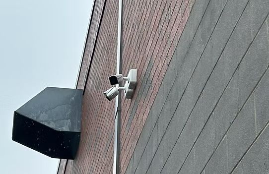 A security camera is mounted on the side of a building.