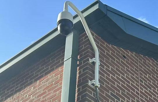 A security camera mounted on the side of a brick building