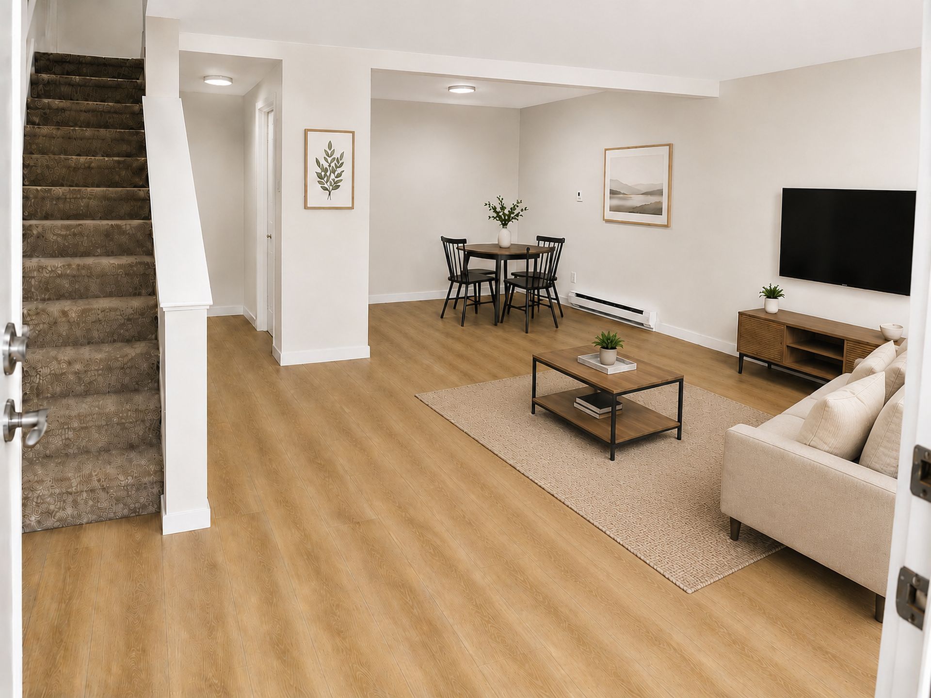 Living room and dining area with beige carpet, staircase, sofa, TV, and a small dining table