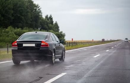 Black Car Driving on A Wet Highway — Bespoke Legal Group In Southport, QLD