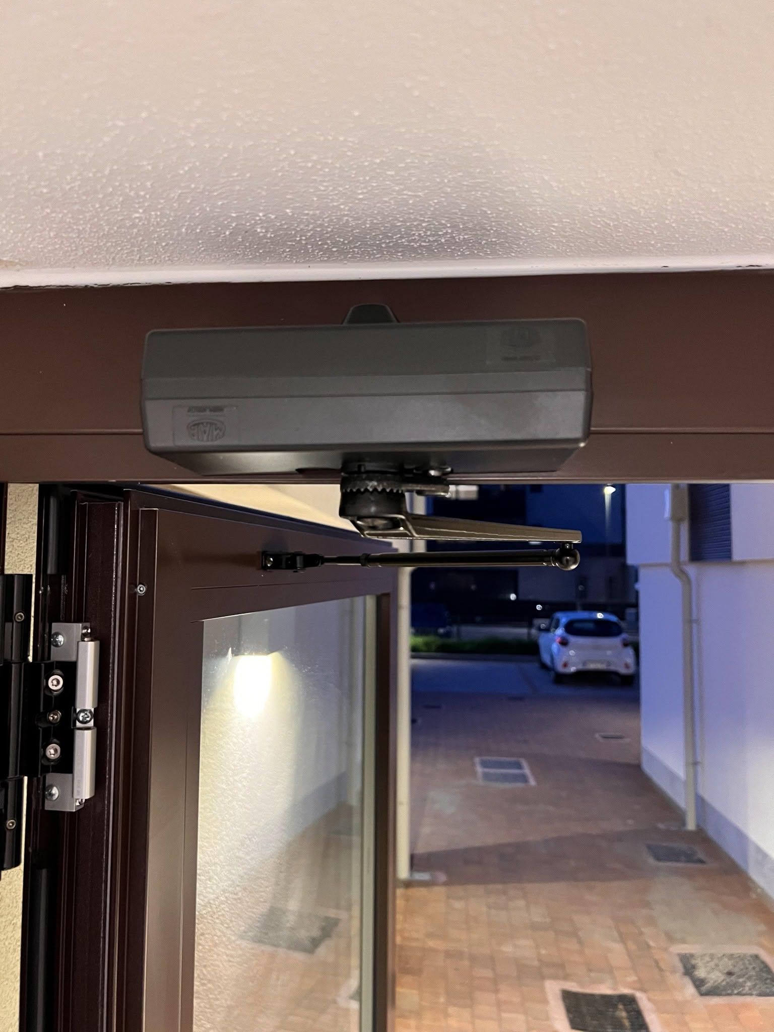 Telecamera di sicurezza montata a soffitto in un parcheggio sotterraneo, puntata verso un corridoio scarsamente illuminato e le auto parcheggiate.