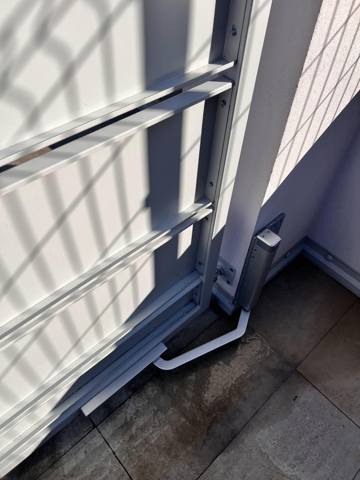 Cancello in metallo bianco con ombre su un patio in cemento e sull'angolo del muro