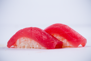 Two pieces of red sushi nigiri on a white surface