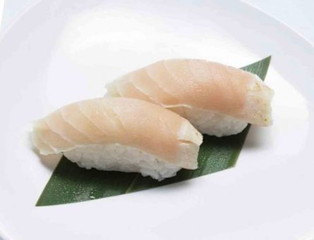 Two pieces of nigiri sushi on a green leaf-shaped plate against a white background