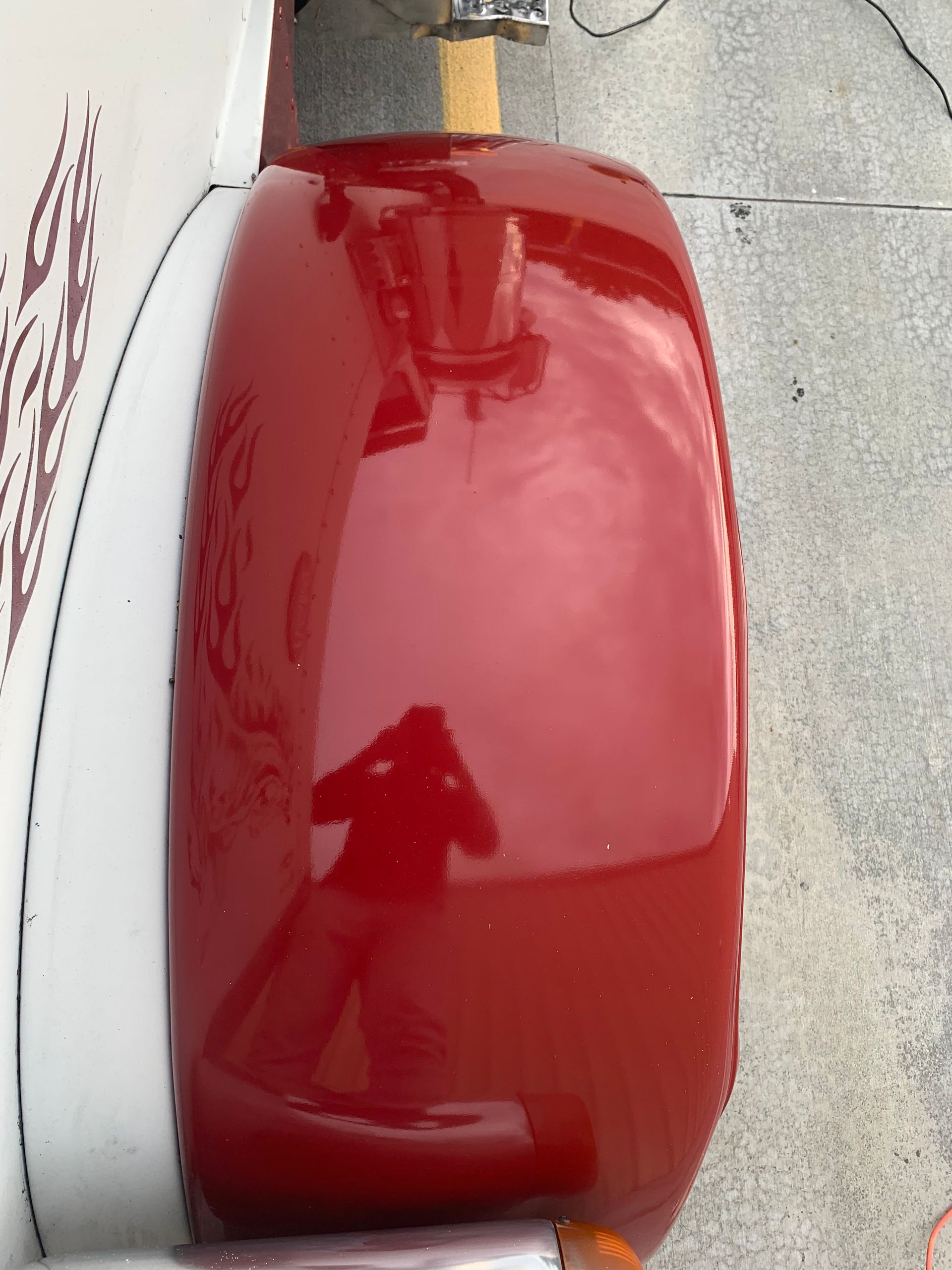 Red, shiny airplane engine cowling with a person's reflection.