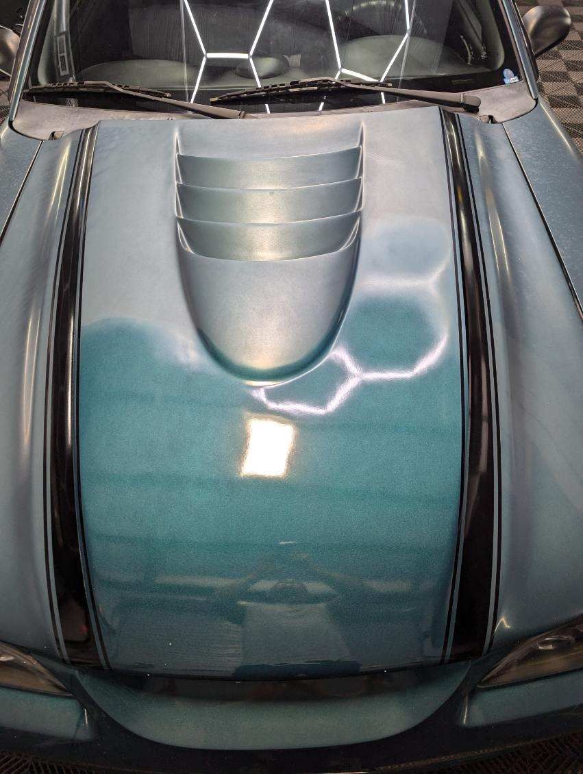 Blue car hood with racing stripes and hood scoop.
