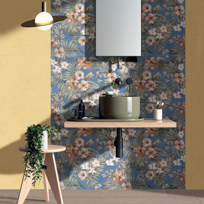 Bagno con carta da parati floreale blu, lavandino color oliva, parete gialla e lampada a sospensione.