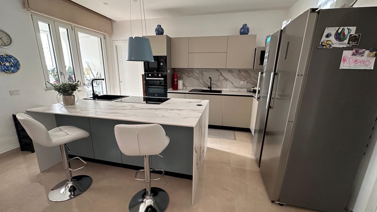 Cucina moderna con isola, sgabelli da bar ed elettrodomestici in acciaio inossidabile.
