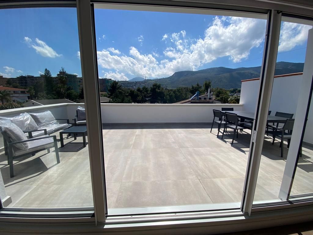 Patio con mobili da esterno e vista sulle montagne, visibili attraverso porte scorrevoli in vetro.