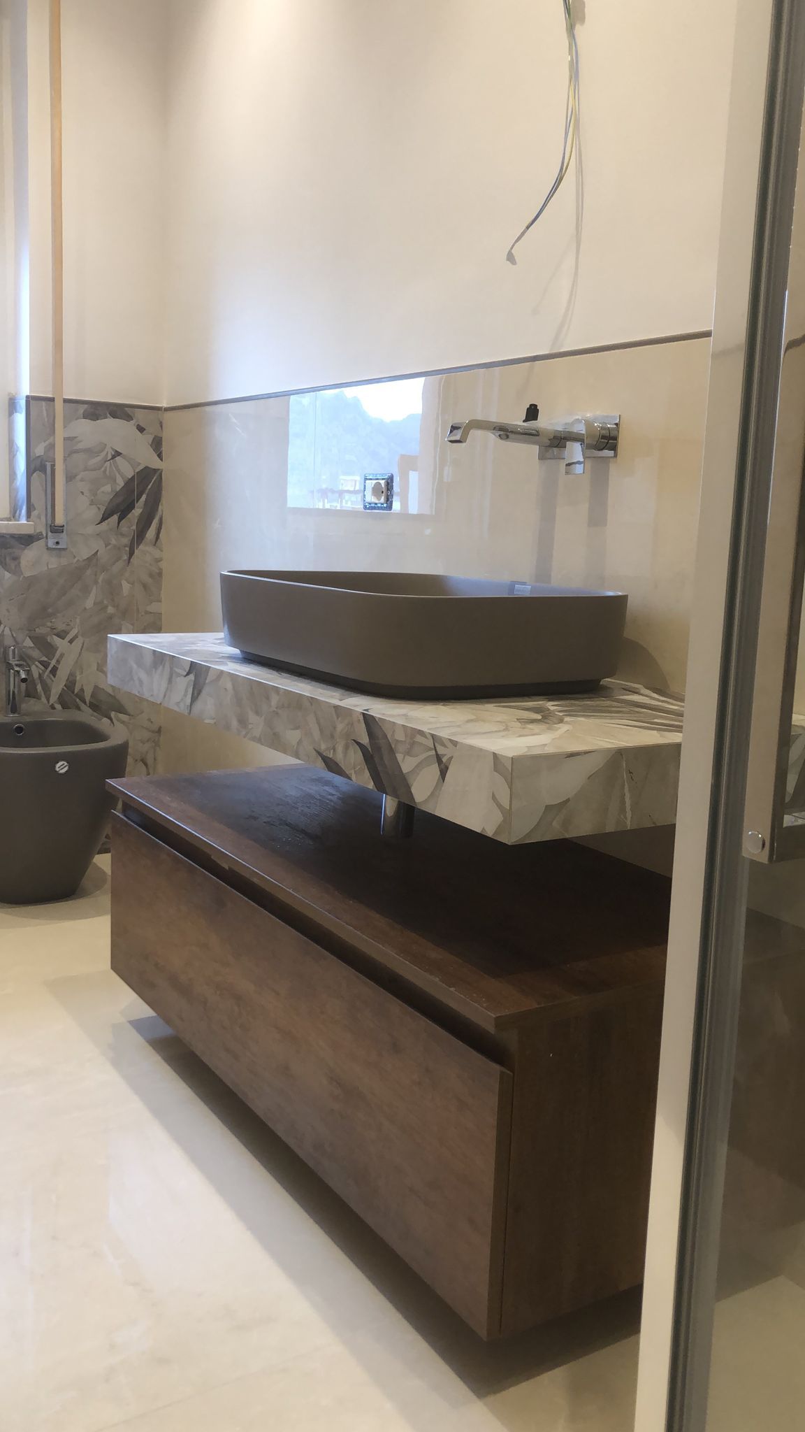 Bagno con piano in pietra, mobile in legno e lavabo grigio.